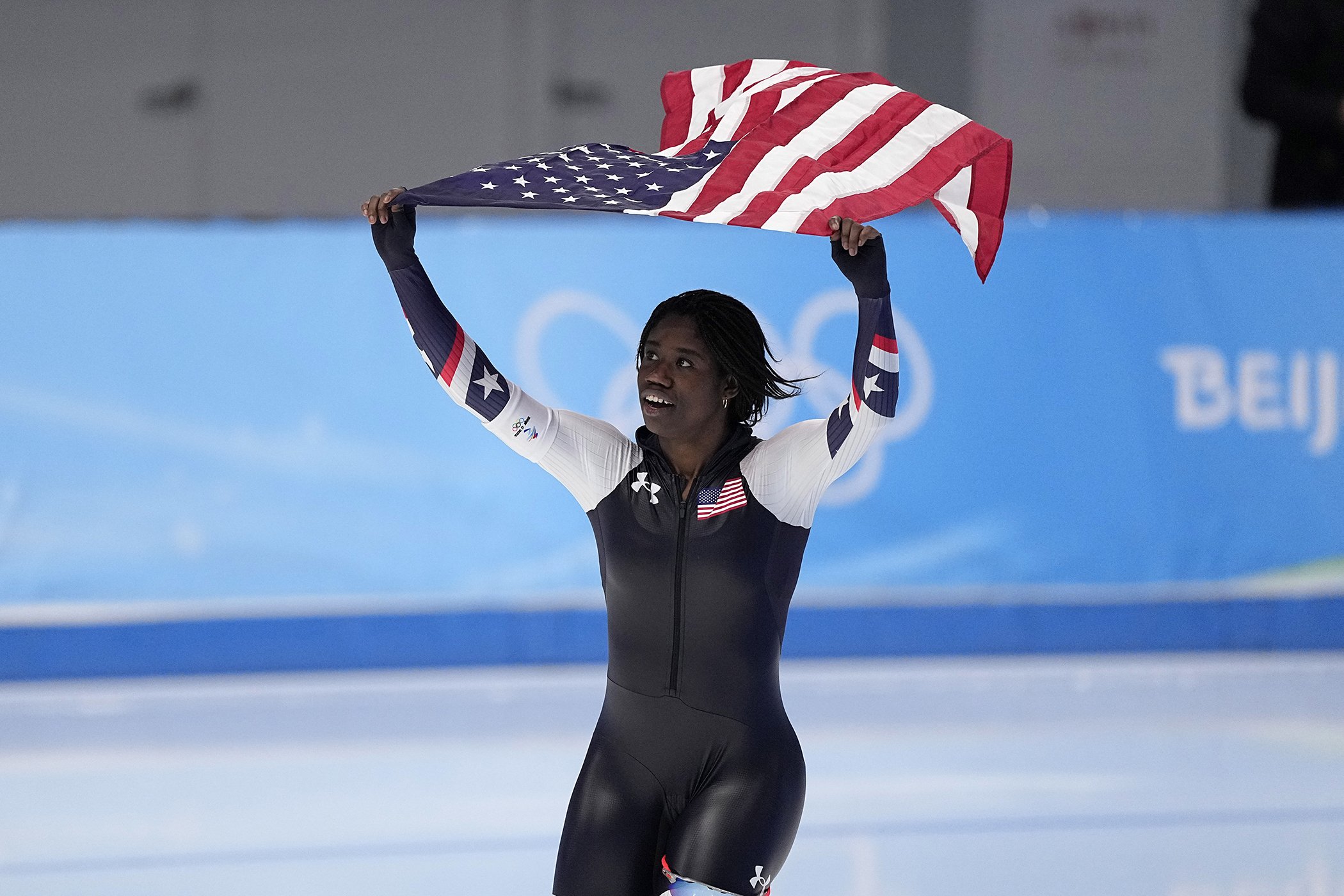 Erin Jackson of the United States hoists an American flag after winning the gold medal in the speedskating women's 500-meter race at the 2022 Winter Olympics, Feb. 13, 2022, in Beijing.