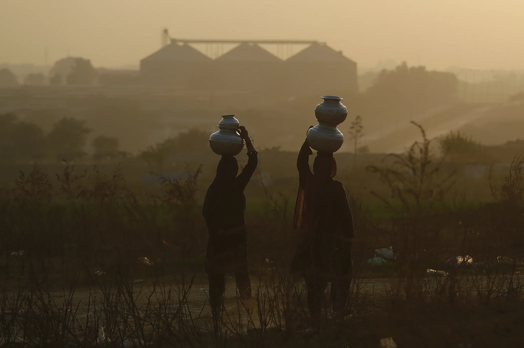 Pakistani nomad women carry water to their houses on the outskirts of Islamabad, Pakistan, in December 2018.