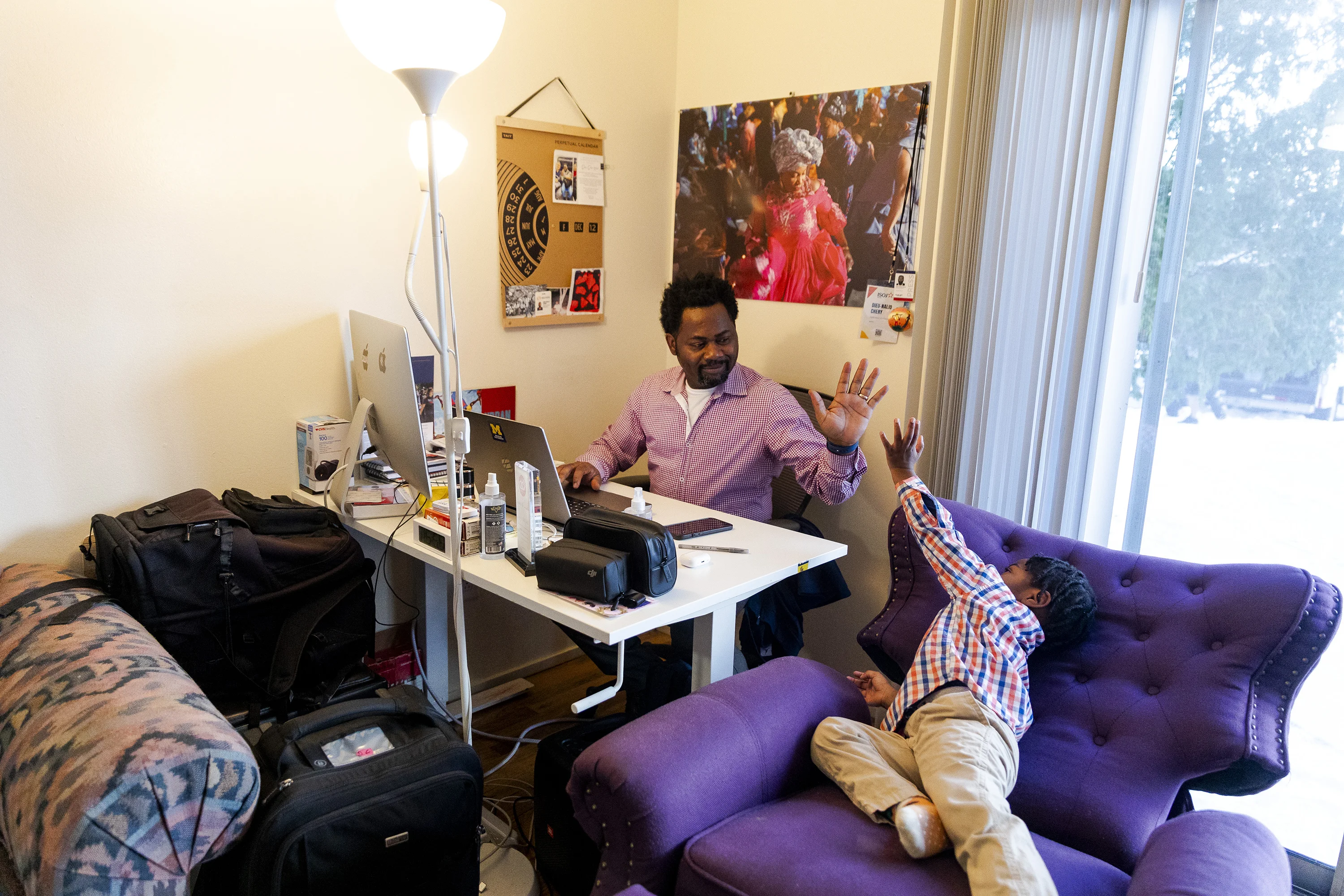 Photojournalist, Dieu-Nalio Chery, high fives his sone, Jahnalio, 3, while he works at his home office on Dec. 12, 2025 in Ann Arbor, Mich.
