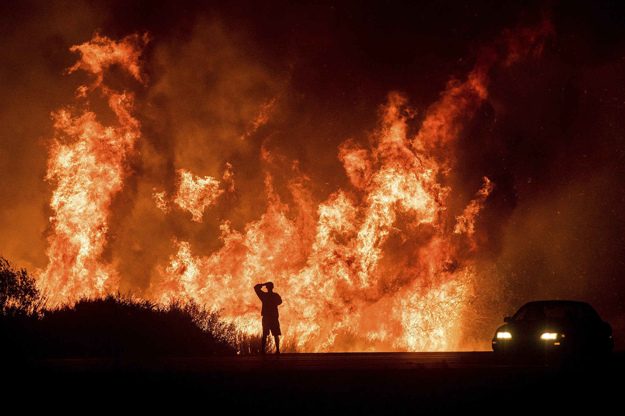 A motorists on Highway 101 watches flames from the Thomas fire leap above the roadway north of Ventura, Calif., on Wednesday, Dec. 6, 2017.  As many as five fires have closed highways, schools and museums and cast a hazardous haze over the region.