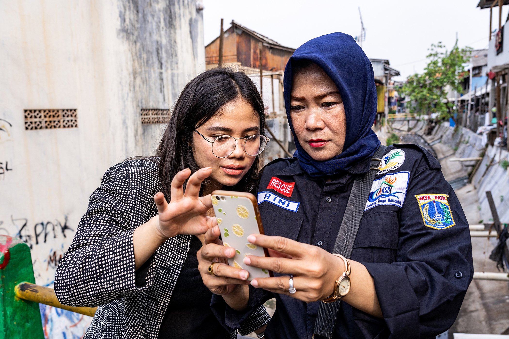 Hotniida AMW Sinambela, Research Operations Co-ordinator of Peta Bencana, demonstrates the functionality of the app on a cell phone at Kelurahan Menteng neighborhood in Jakarta, an area prone to flooding.