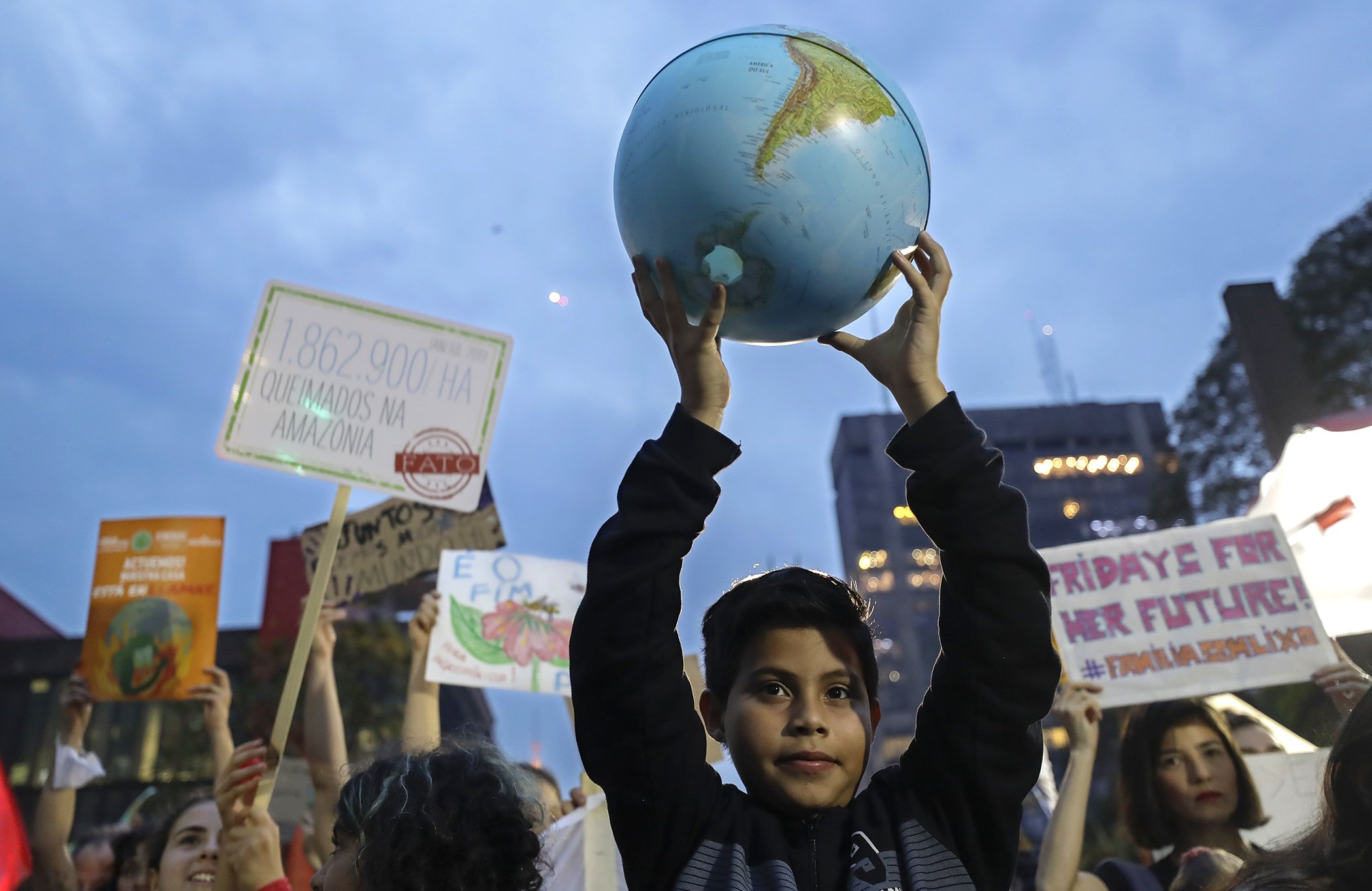 A boy holds up a small globe during a global protest on climate change in Sao Paulo, Brazil, Sept. 20, 2019. Across the globe, hundreds of thousands of people took to the streets to demand that leaders tackle climate change in the run-up to a UN summit.