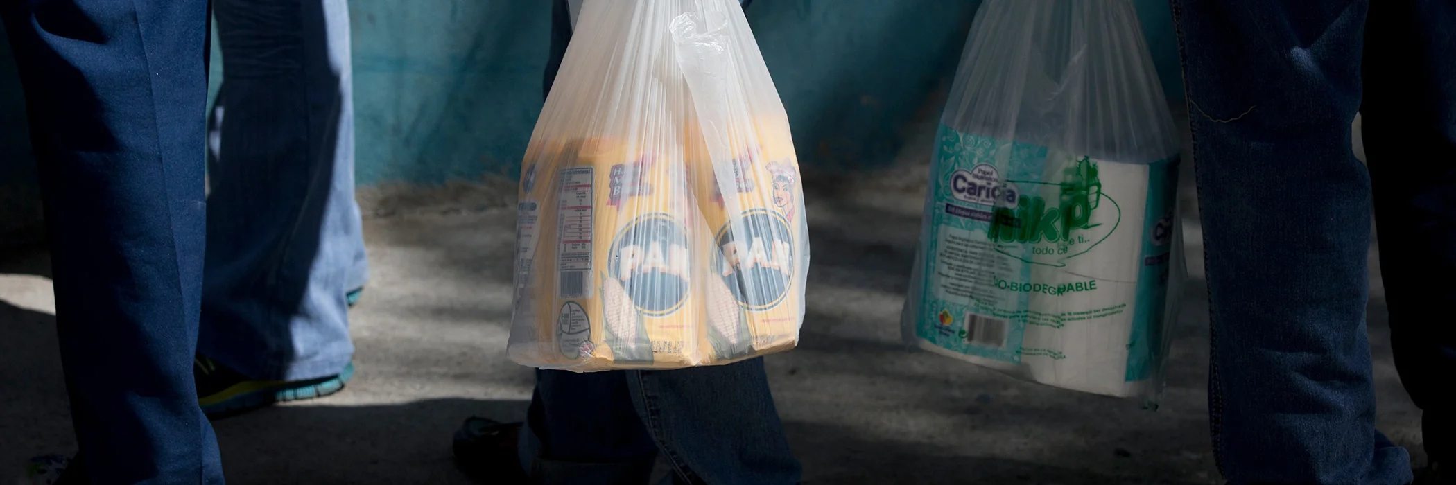 Customers hold their shopping bags of newly bought corn flour and toilet paper as they line up outside a private supermarket in Caracas, Venezuela, Jan. 16, 2015.