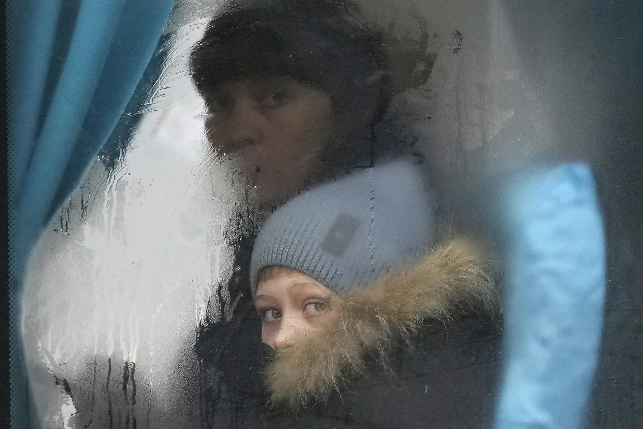 A woman and child peer out of the window of a bus as they leave Sievierodonetsk, the Luhansk region, eastern Ukraine, Feb. 24, 2022.