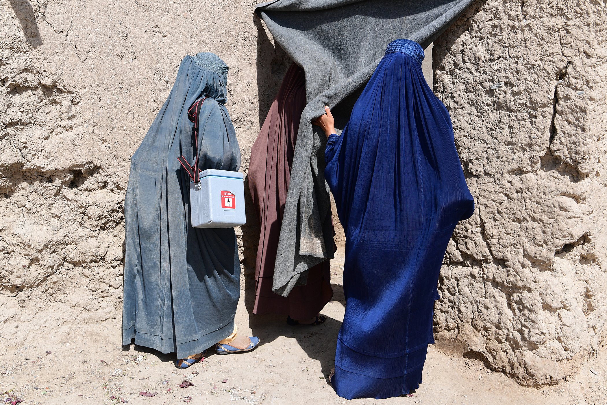 Health care workers are pictured outside of a home prior to vaccinating a child during a polio social mobilization activity in the community, in Kandahar, in the southern region of Afghanistan on March 8, 2020.