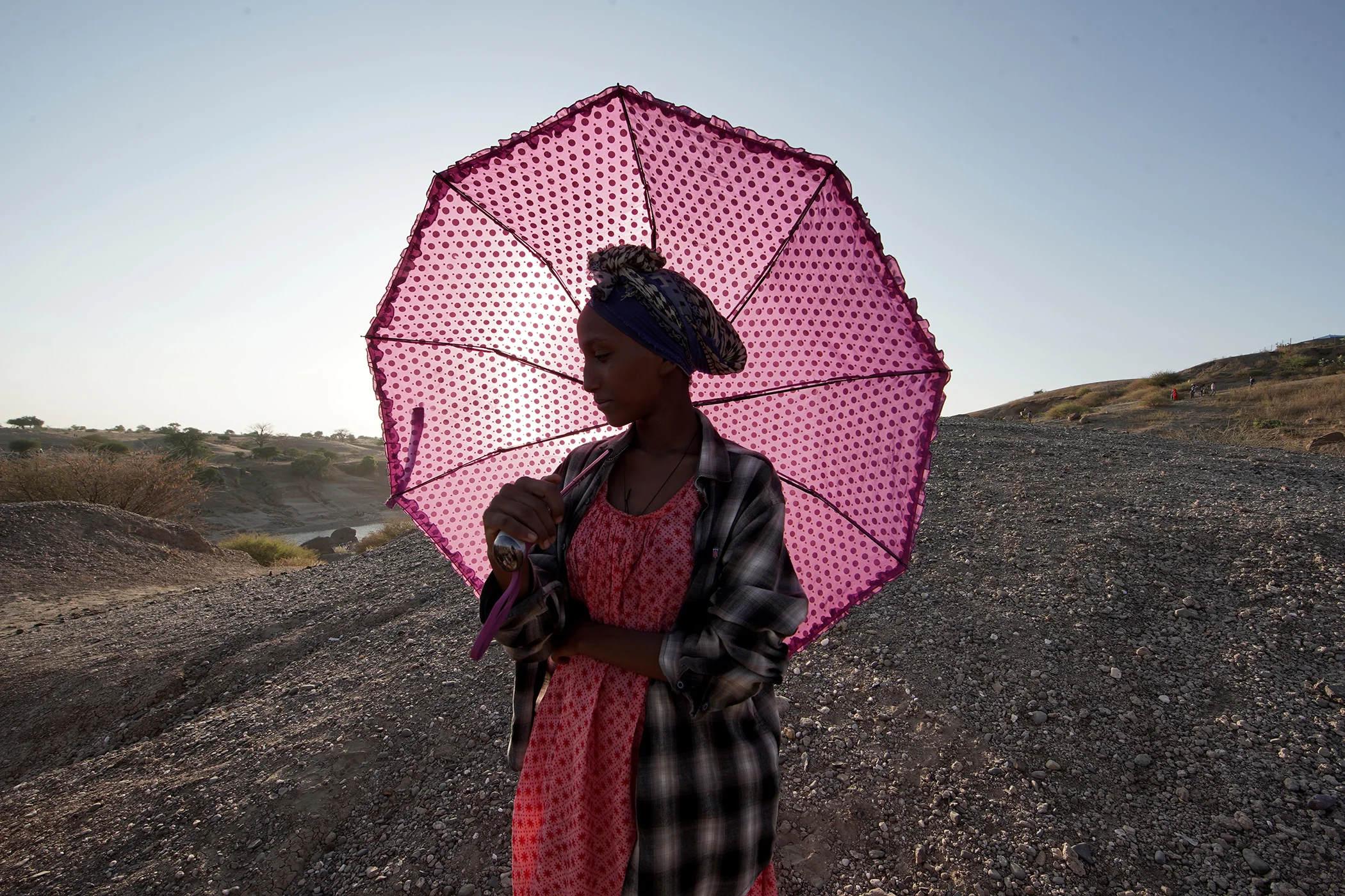 A refugee from Ethiopia,  who is fleeing clashes in the country's Tigray region, shades herself from the sun after crossing the border into Hamdayet, Sudan, with her family.