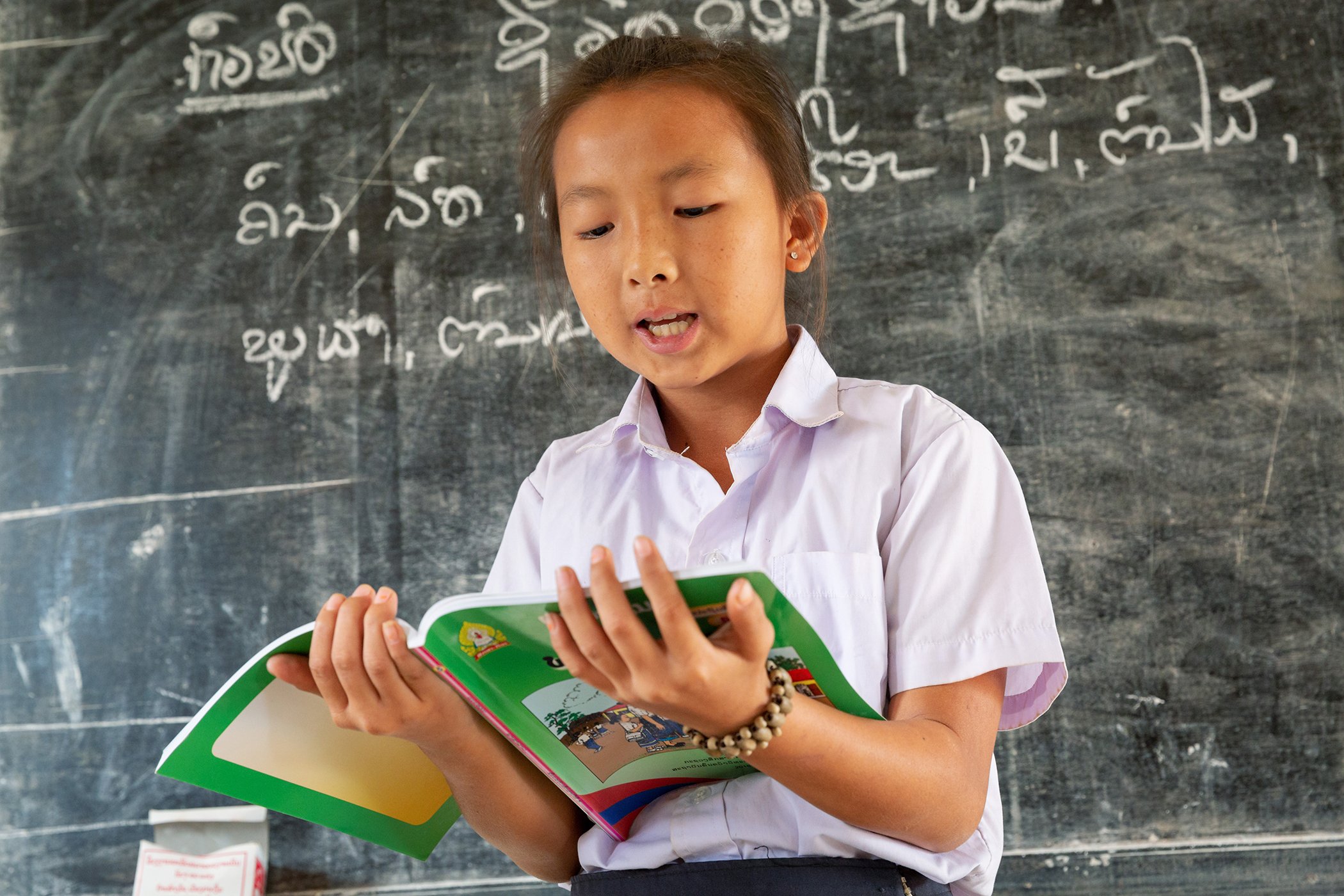 A grade five student reads in front of the class at Phonsivilay Primary School, Meun District, Lao PDR, December 2018.