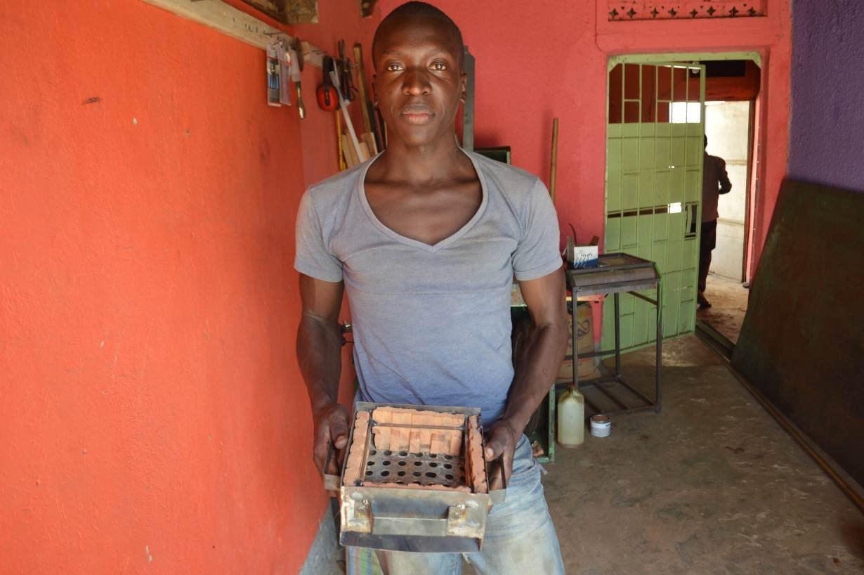 Morris Opiyo shows off a stove that uses eco-friendly briquettes or garden waste to produce heat in Kampala, Uganda, May 13, 2019.