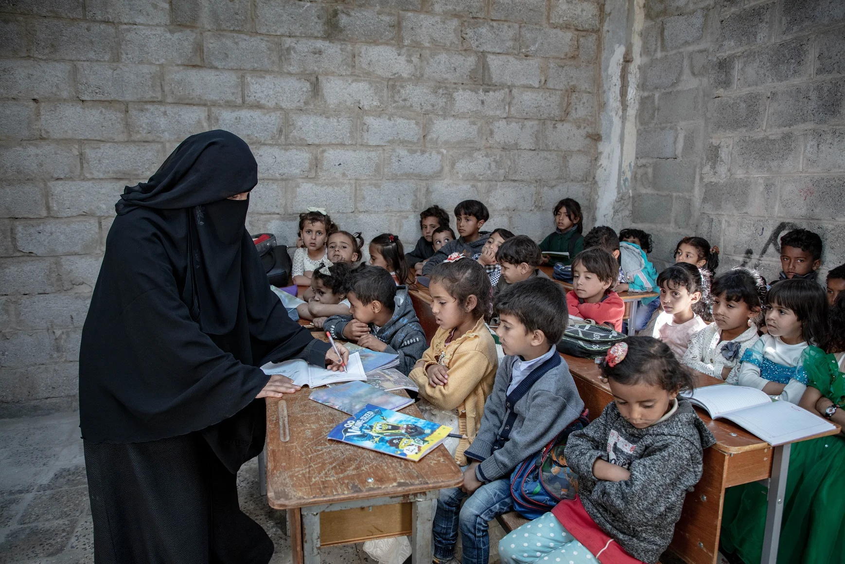 A teacher in Yemen stands in her classroom, helping children keep learning despite years of conflict. Education in emergencies provides children safety, stability, and hope for the future.