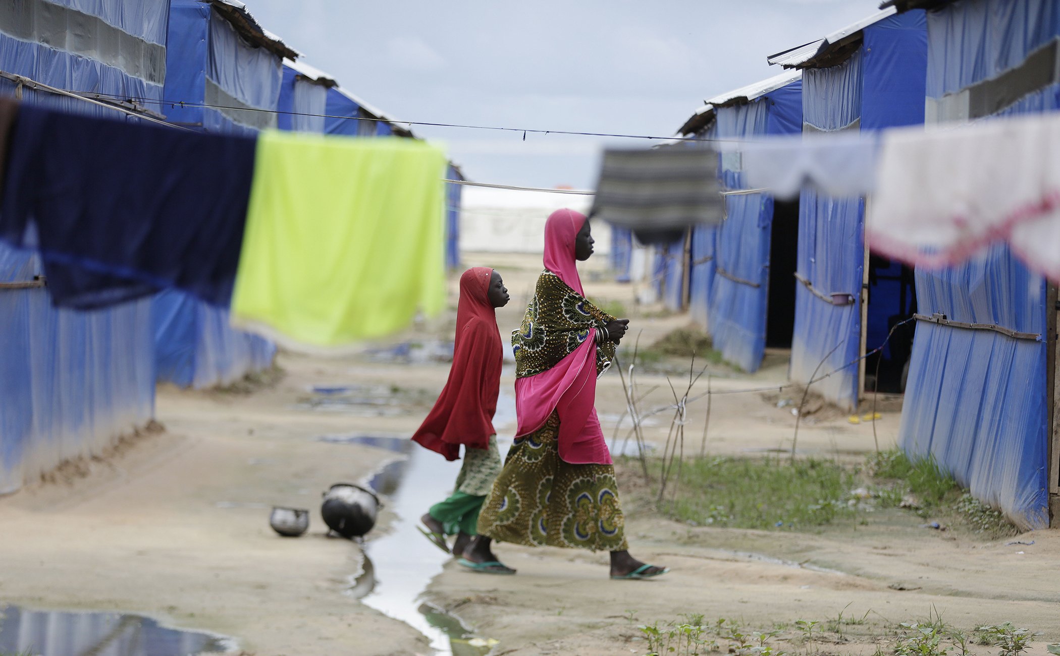 A woman and her child walk past the laundry at a camp for displaced people in Maiduguri, Nigeria, August 2016.