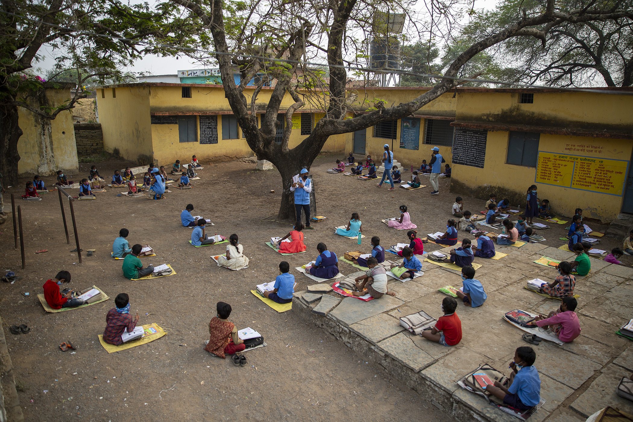 Volunteers teach children outside in the school compound in the village Munda, district Baloda Bazar, Chattisgarh, India, Dec. 17, 2020.