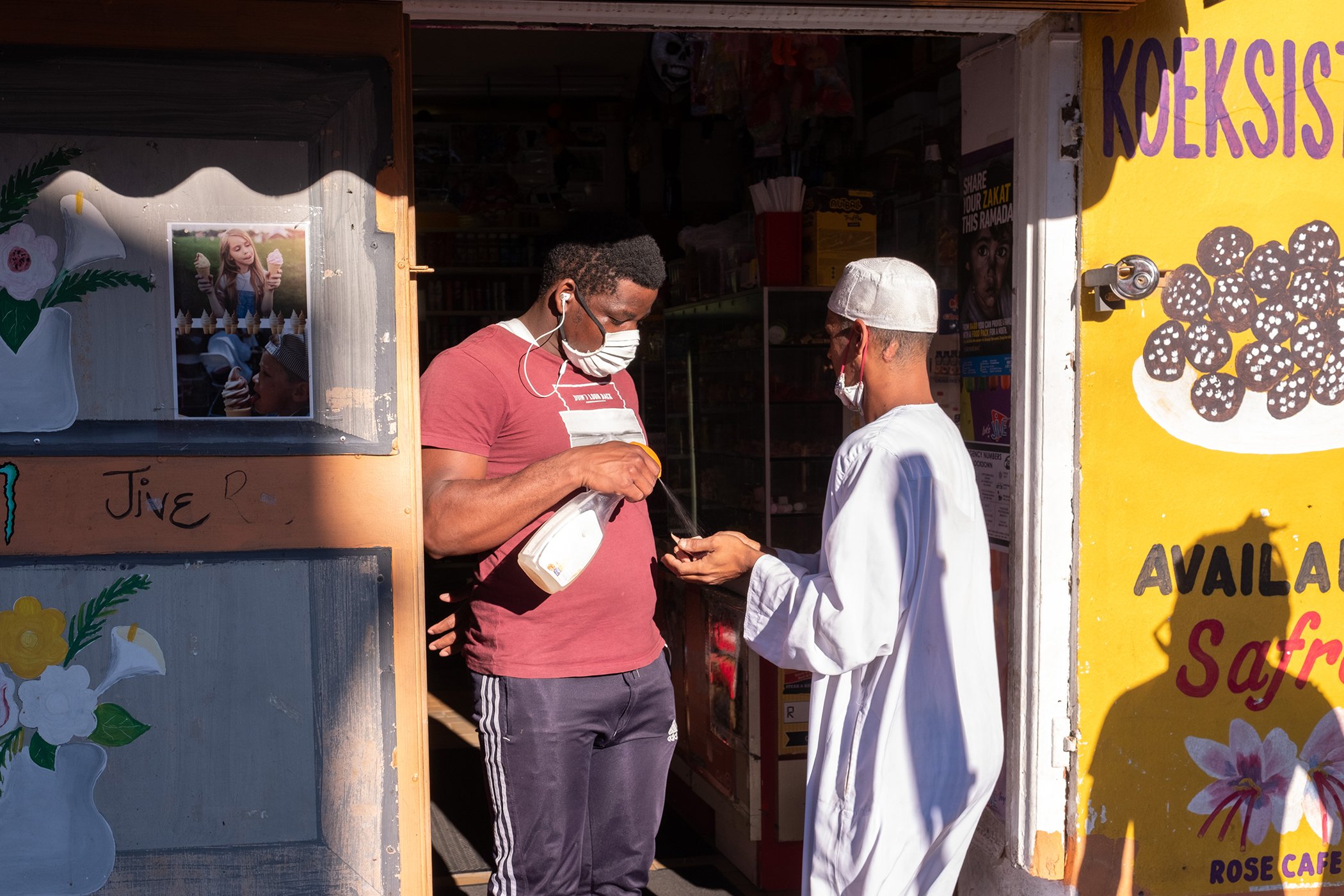 A doorman sanitizes a man’s hands before he is allowed to enter a corner shop in Bo-kaap, Cape Town, in April 29, 2020 during the COVID-19 pandemic.