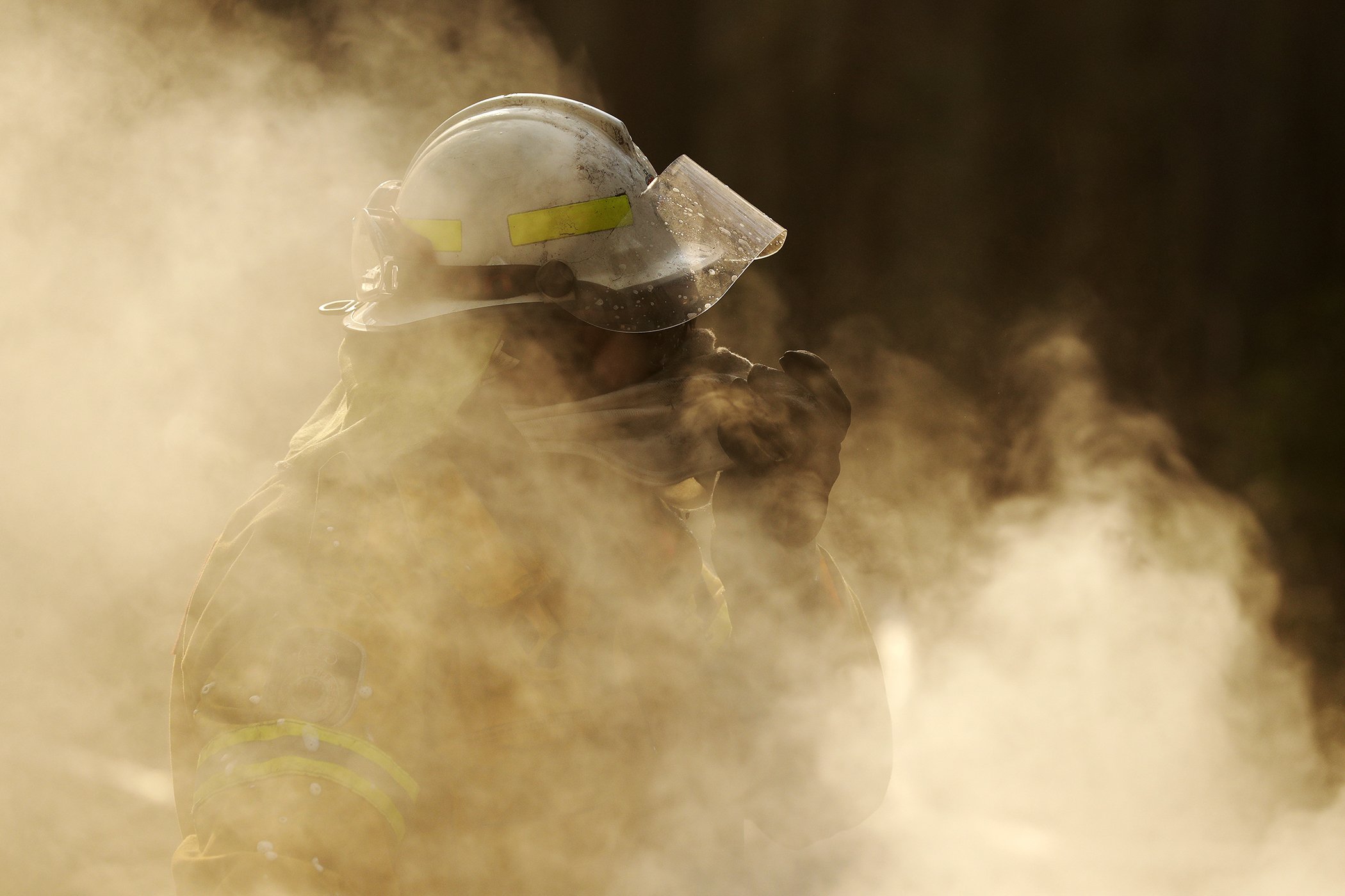 A firefighter covers his face from block smoke as he battles a fire near Bendalong, Australia, Jan. 3, 2020.