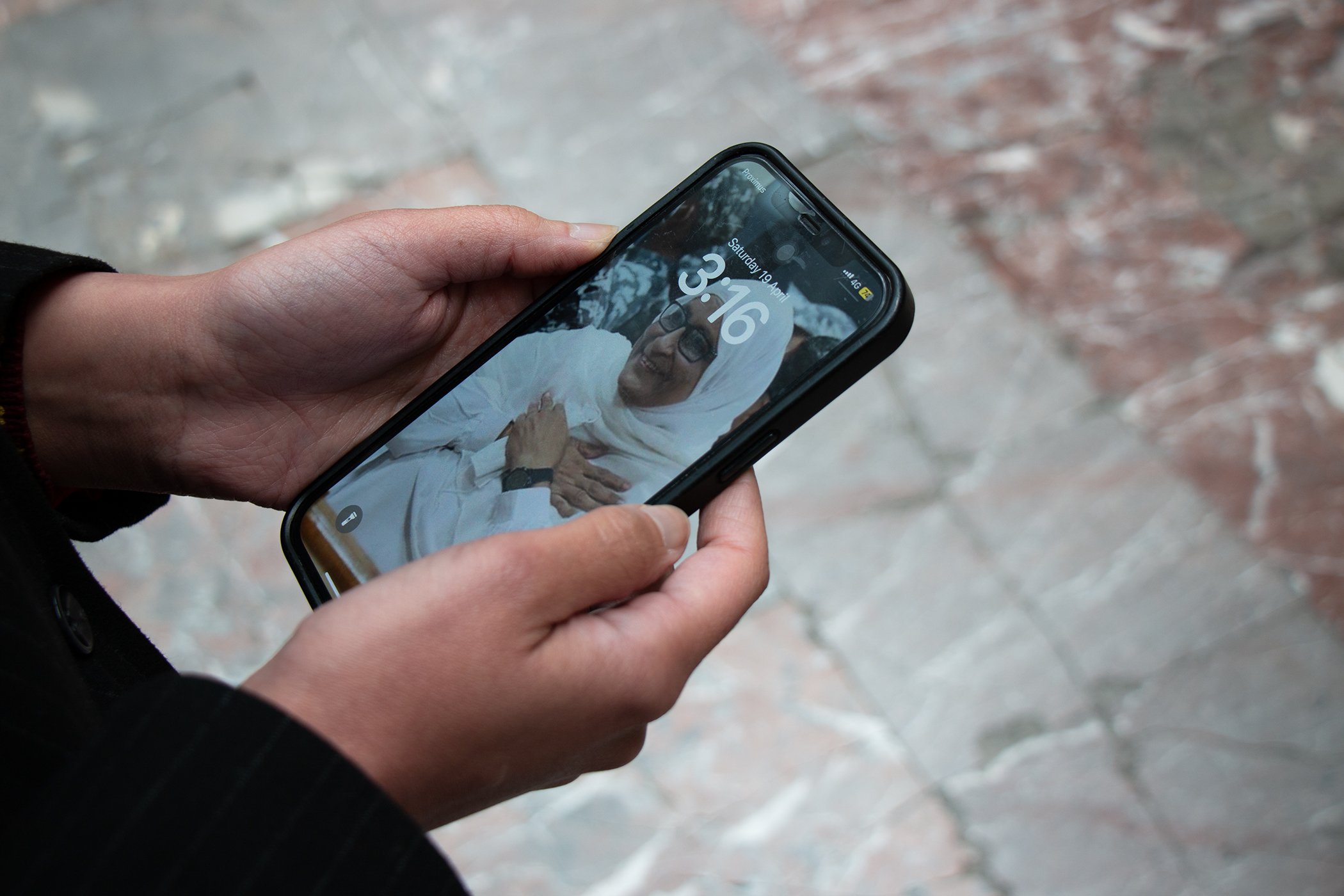 View of Gehad Khaled's hands as she holds her phone displaying an image of her mother, Hoda Abdel Moneim, as her screensaver.