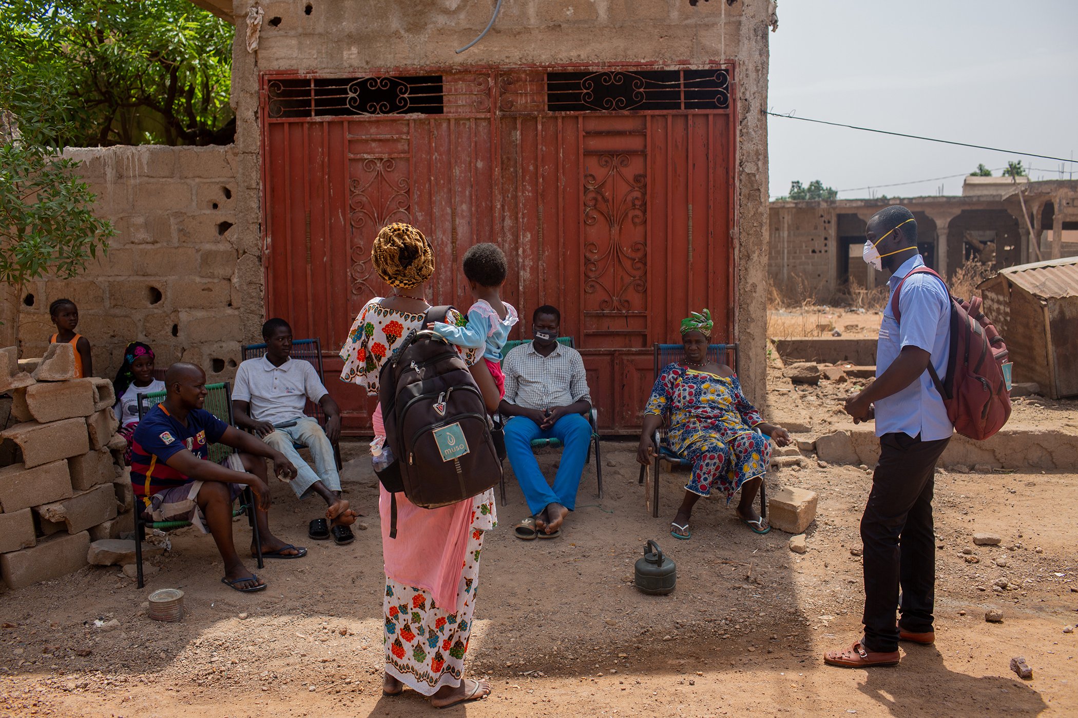 Seba Samake, a Muso CHW and Amadou Komina, a CHW Supervisor, speak to a group on the street in Samake's neighborhood of Bamako, Mali in between visits to local homes to raise awareness about COVID-19 and precautions that can be taken to protect residents.