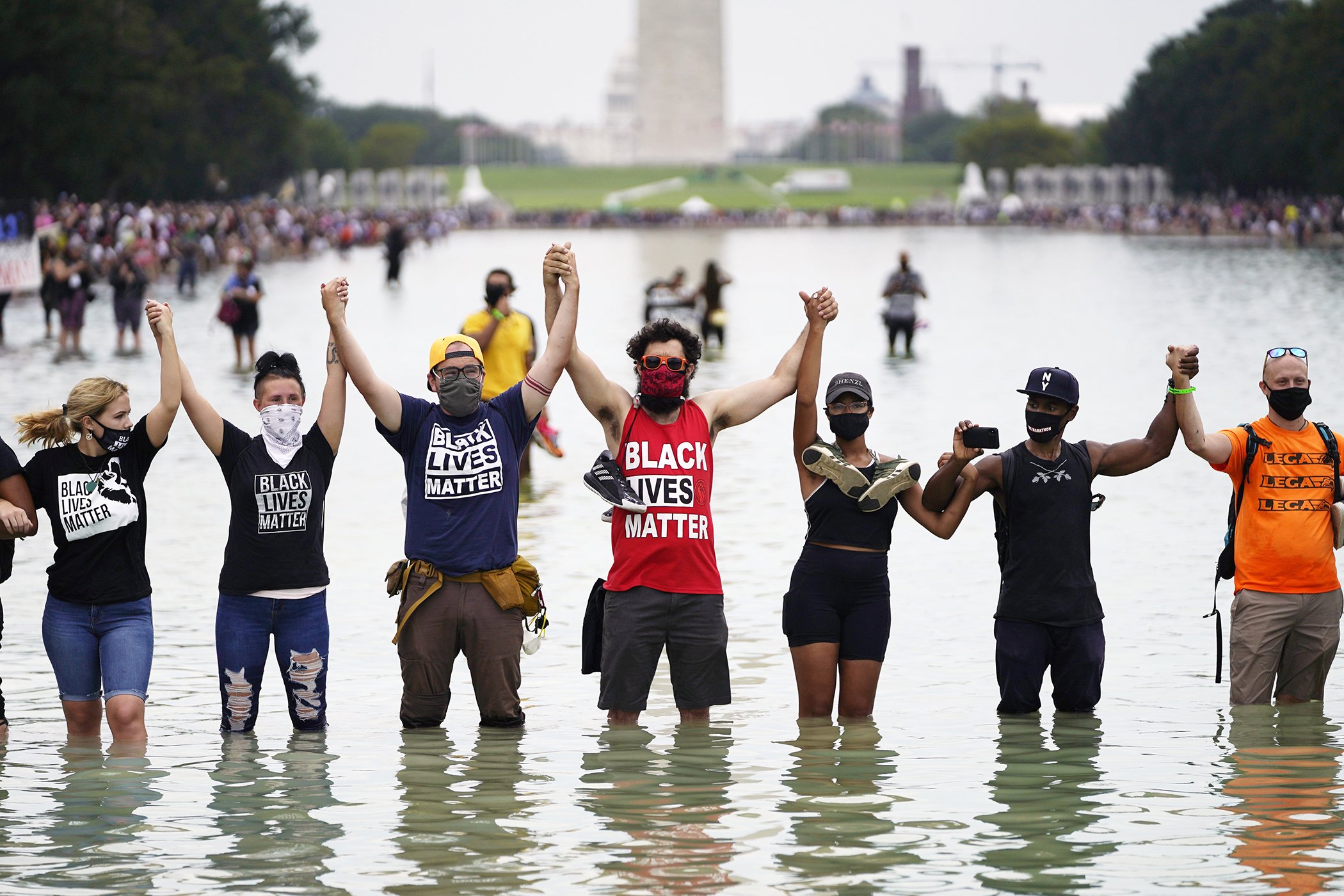 People pose for a photo in the Reflecting Pool in the shadow of the Washington Monument as they attend the March on Washington, Aug. 28, 2020, at the Lincoln Memorial in Washington, DC.