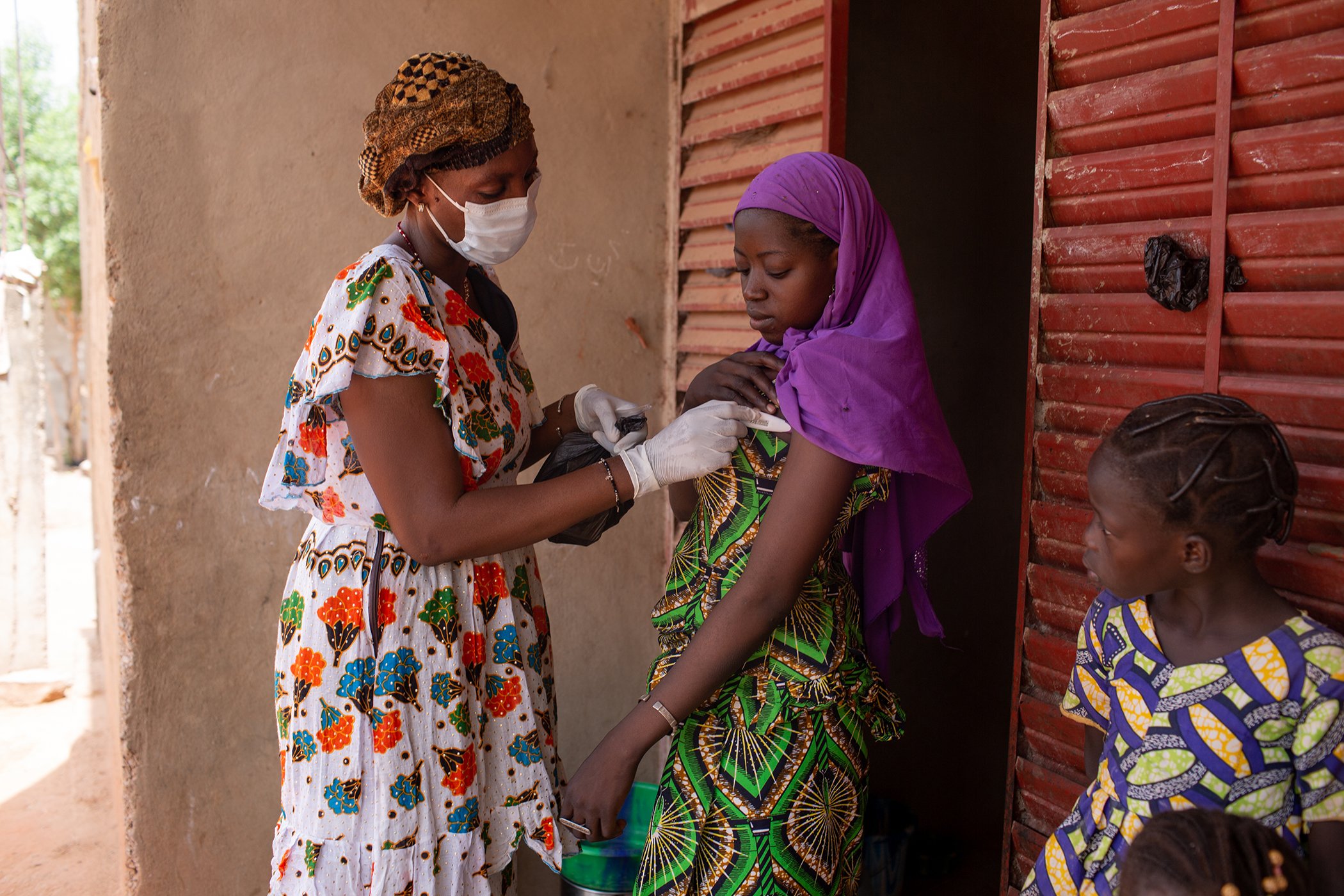 Seba Samake, a Muso CHW, takes the temperature of Koniba Coulibaly, who was recently a patient at the Yirimadio CSCOM, as part of a follow up visit.