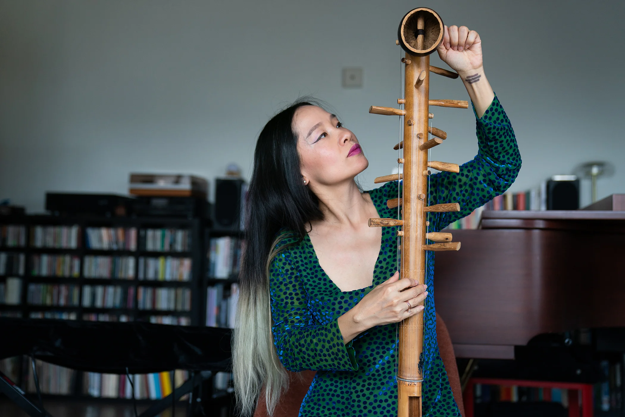 Mai Khôi, tunes a ‘Dinh Goong’ instrument in her home in Philadelphia, PA on Aug. 12, 2026.
