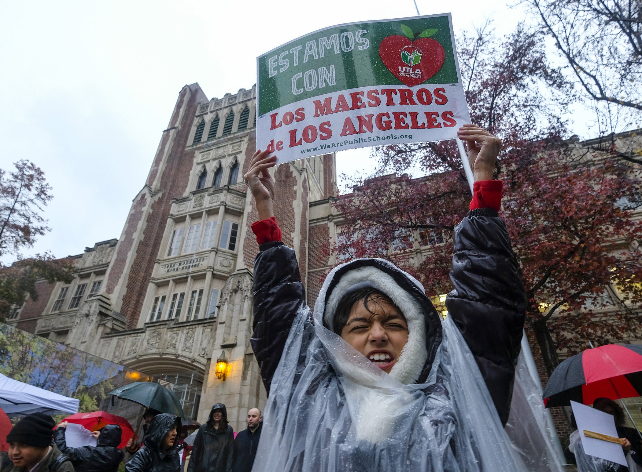 Alessandro Niculescu, 10, holds up a sign in the rain during a teacher strike outside John Marshall High School, Jan. 14, 2019, in Los Angeles.