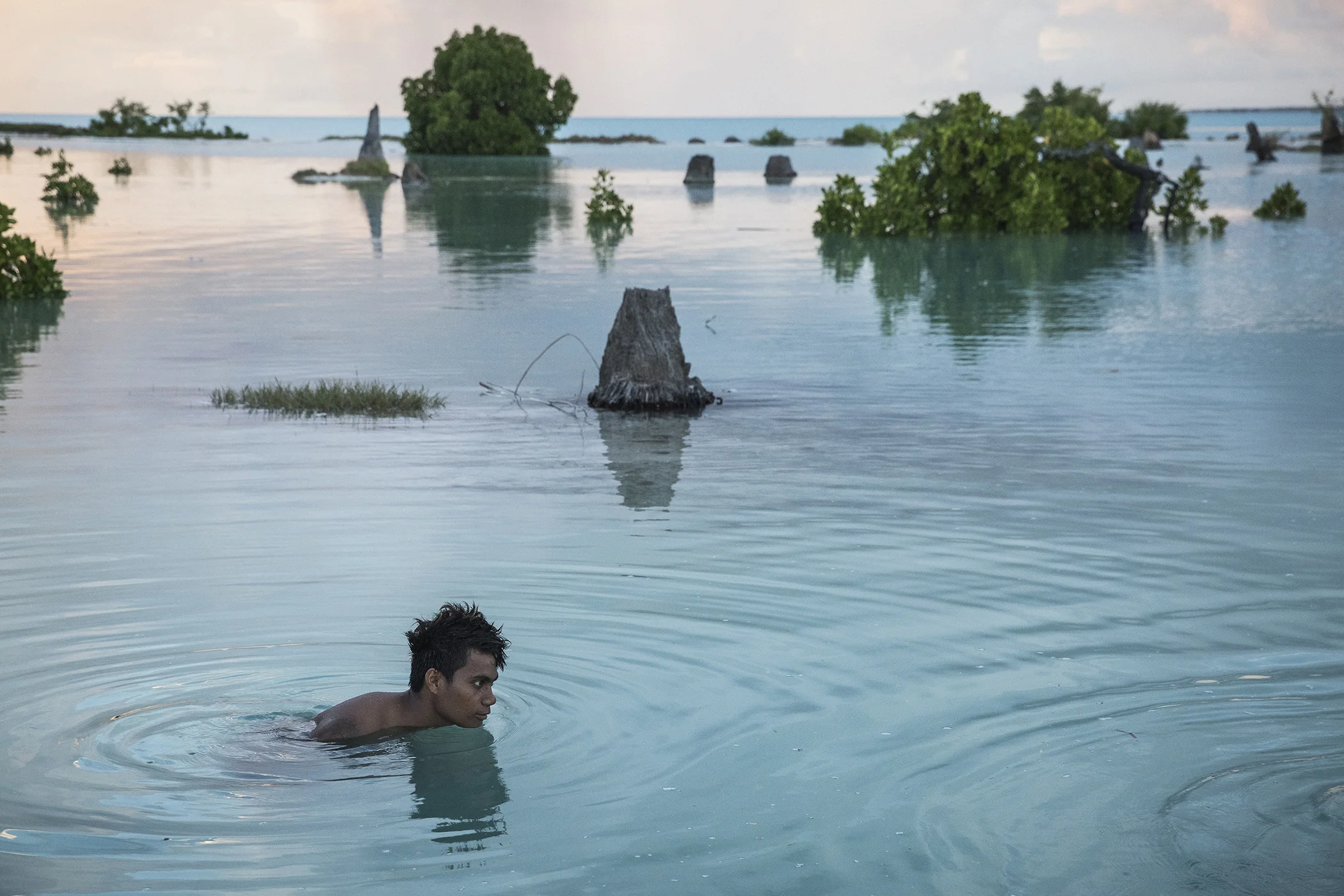 Peia Kararaua, 16, swims in the flooded area of Aberao village in Kiribati, one of the countries most affected by sea level rise. During high tides many villages become inundated making large parts of them uninhabitable.