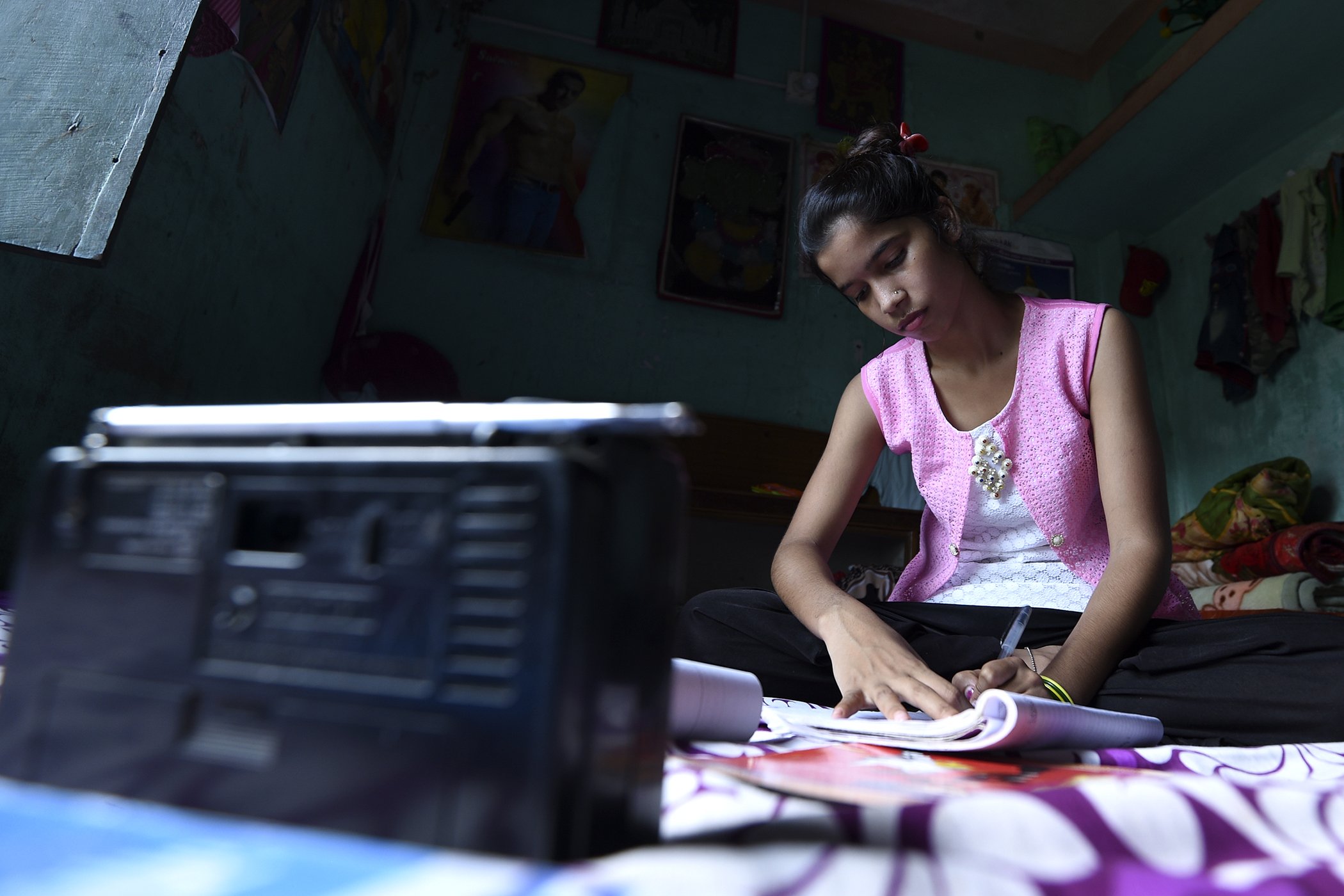 Little Sister Anjali patel listens to a radio program for her studies.