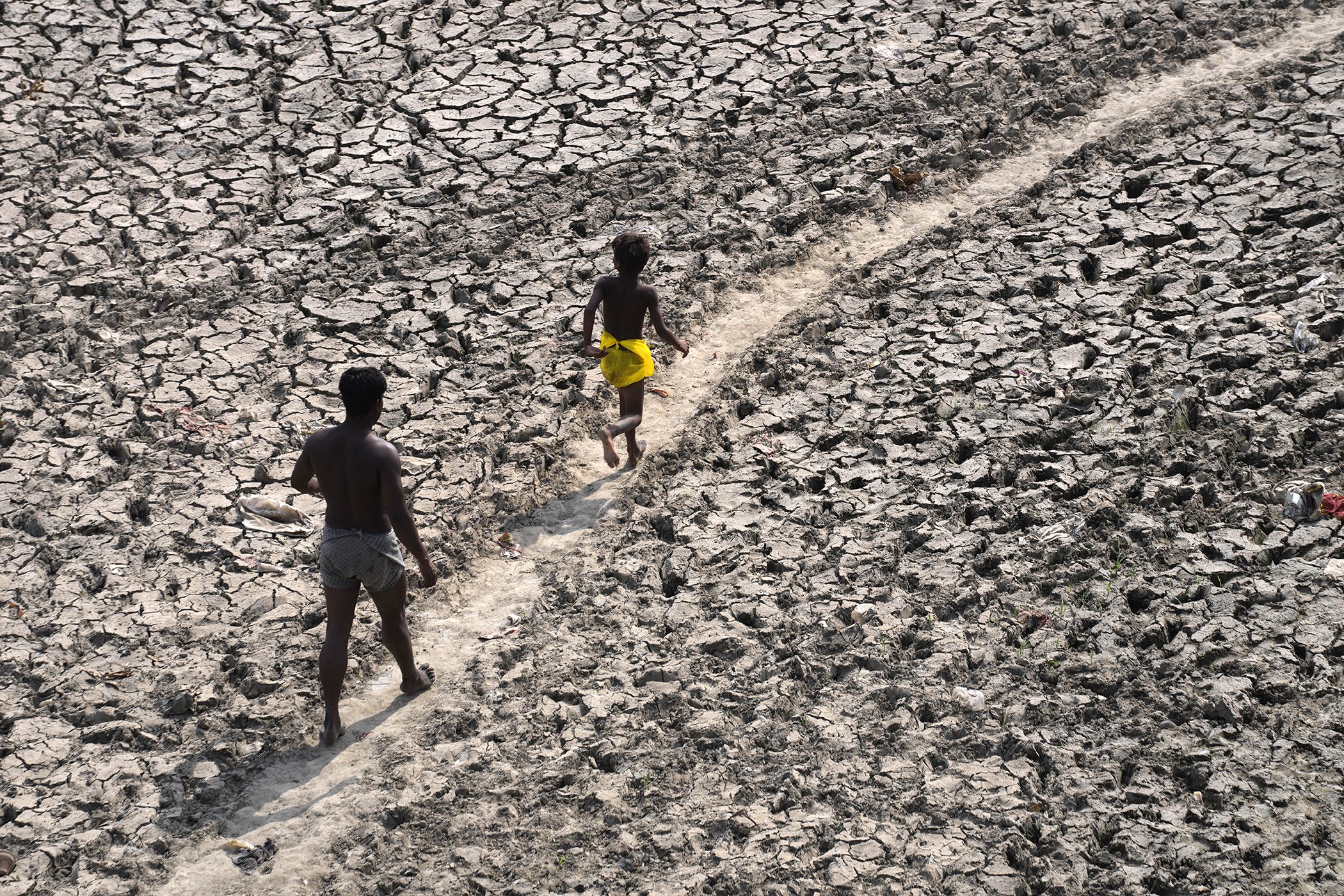 A man and a boy walk across an almost dried up bed of river Yamuna following hot weather in New Delhi, India, May 2, 2022.