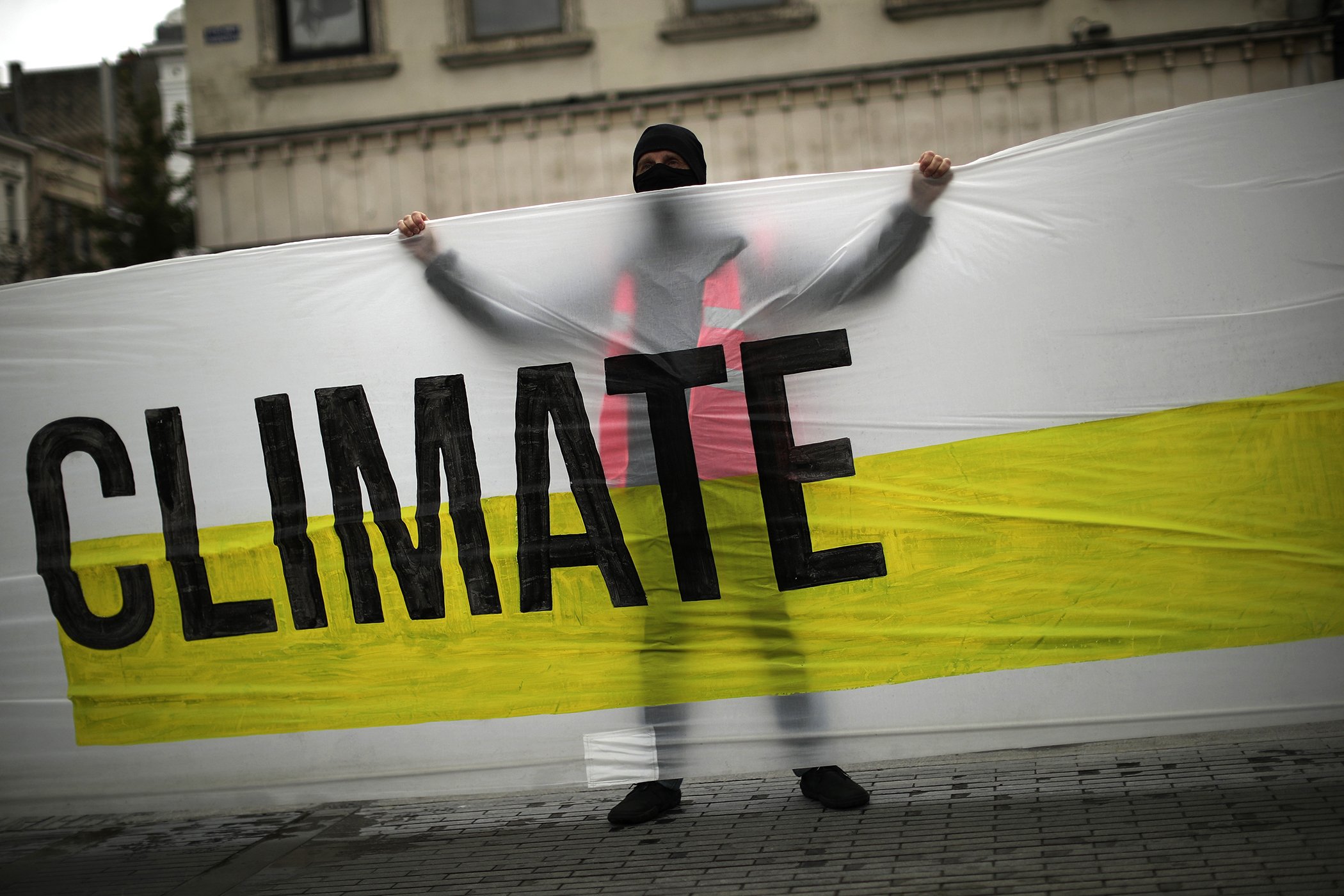 A man, wearing a mask to prevent the spread of the coronavirus, holds a banner that reads: "United for climate" during a small climate change protest in downtown Brussels, Sept. 25, 2020.