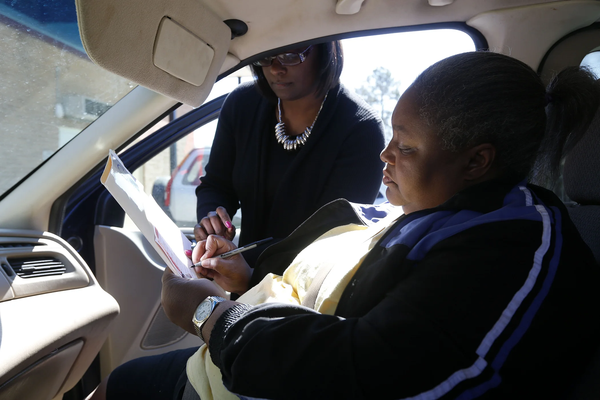 Deborah Muldrow, who could not enter the polling place due to a physical disability, receives assistance from poll manager Adrain Roman, left, as she votes curbside for the South Carolina Democratic primary in Sumter, S.C., Feb. 27, 2016.