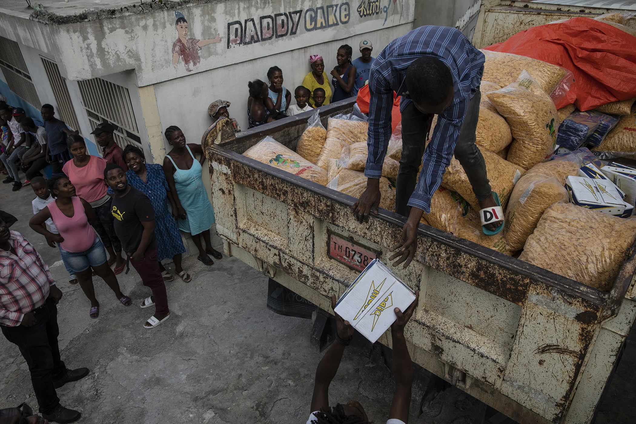 A worker stands on a truckload of corn flakes donated from the AAA political party to residents in the gang-controlled Bel Air neighborhood of Port-au-Prince, Haiti, Oct. 5, 2021.