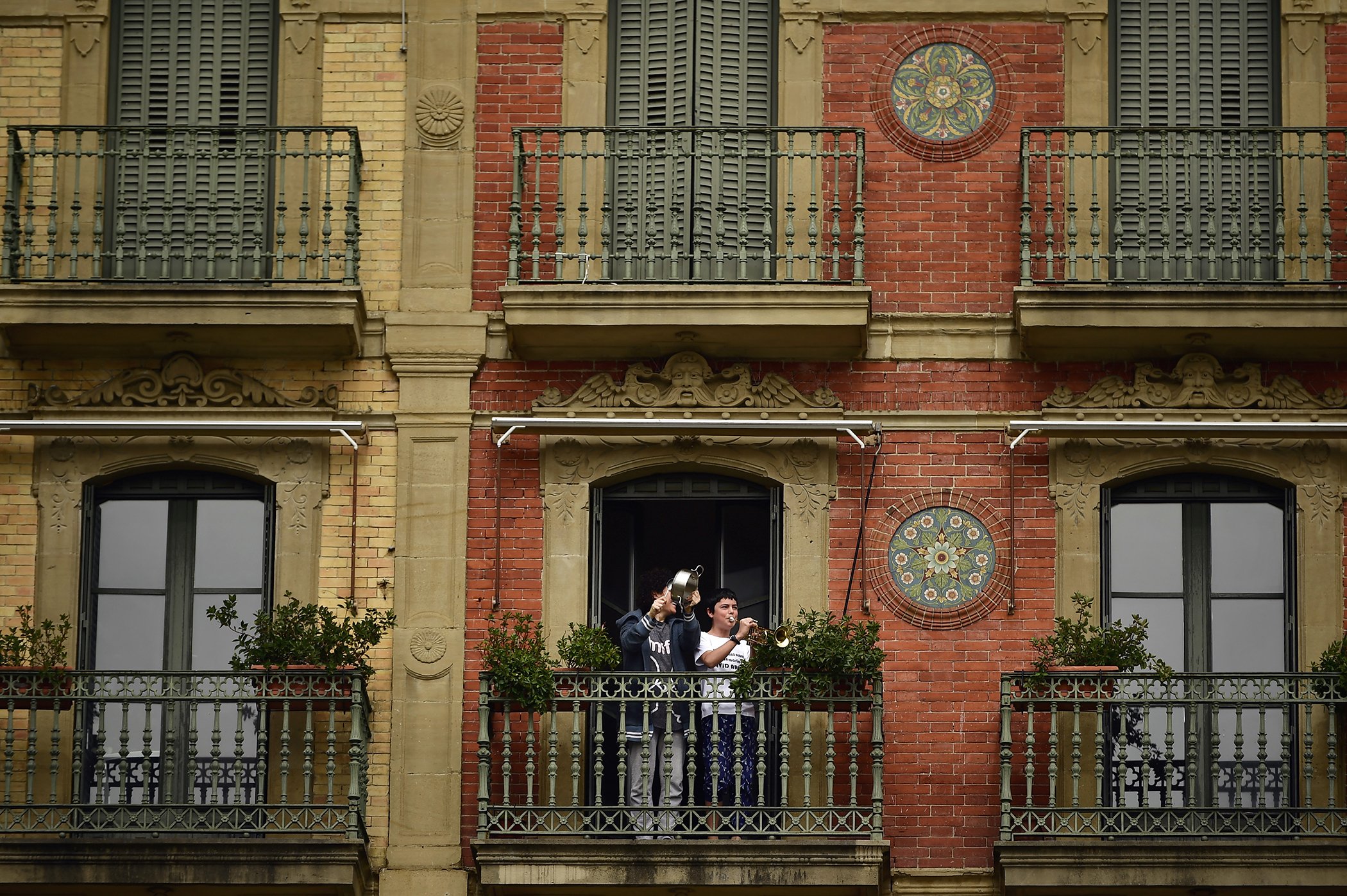 A young boy plays his trumpet from a balcony, in Pamplona, northern Spain, Wednesday, March 18, 2020.