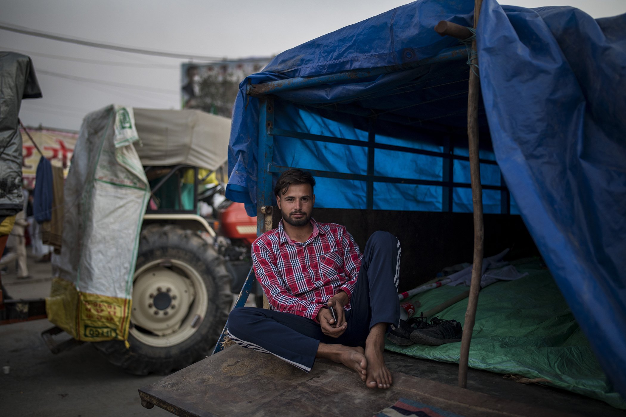 Farmer Sikandar Machhonda, 22, sits at the back of his tractor trailer parked on a highway in a sign of protest against new farm laws, at the Delhi-Haryana state border, India, Dec. 2, 2020. The convoy stretches for at least three kilometers (1.8 miles).