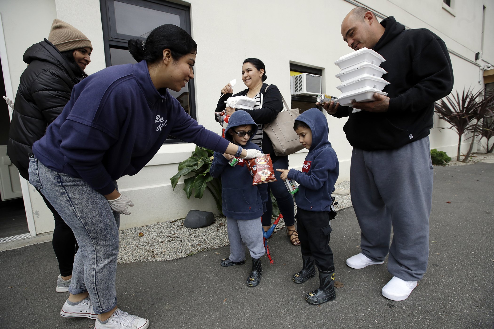 Volunteer, Pahola Campos hands out lunches to the Garcia family at a food distribution center set up by the Dream Center for those in need due to the coronavirus outbreak, March 16, 2020, in Los Angeles.