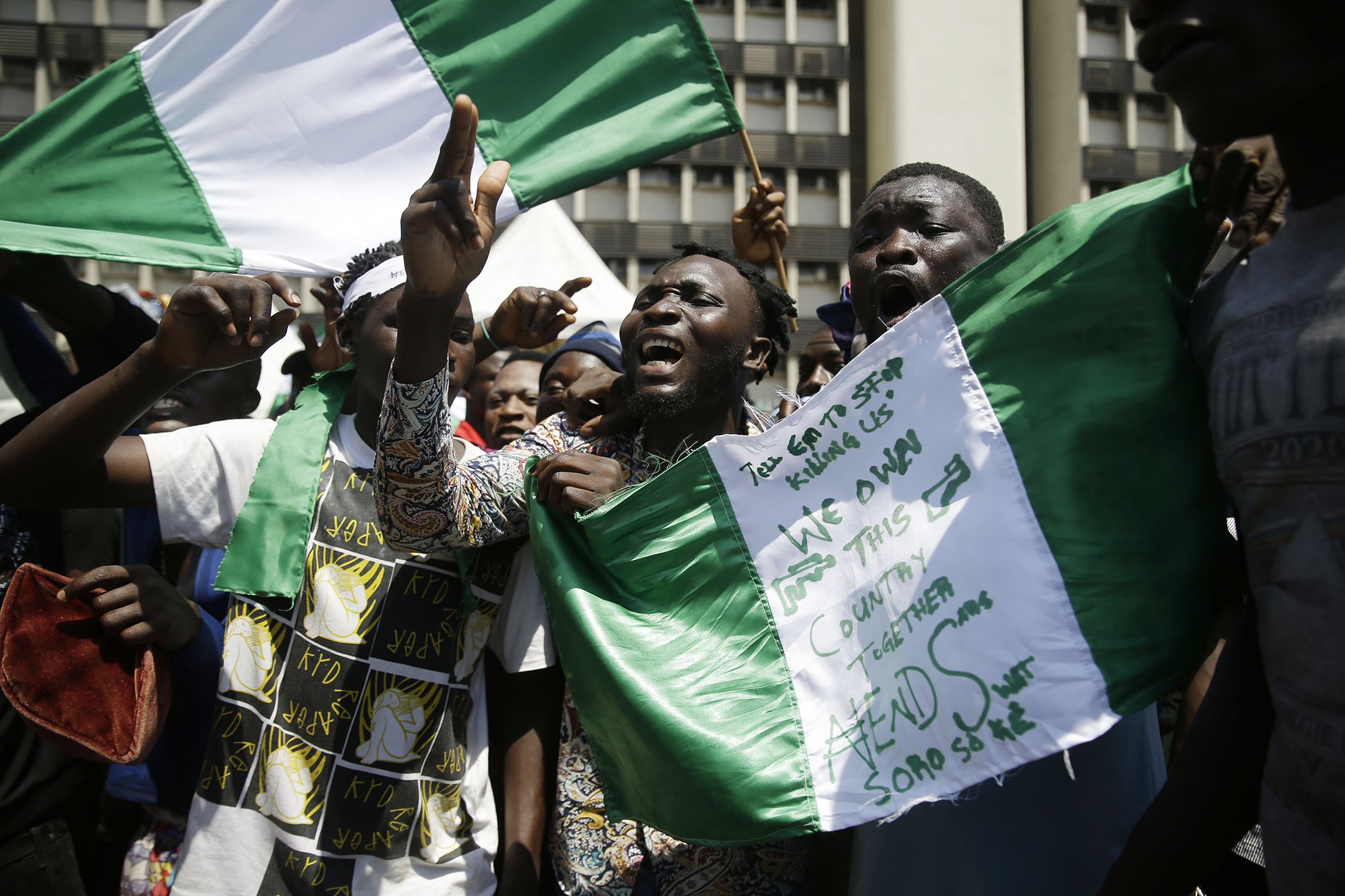 People hold banners as they demonstrate on the street to protest against police brutality, in Lagos, Nigeria, Oct. 20, 2020. After 13 days of protests against police brutality, authorities have imposed a 24-hour curfew in Lagos, Nigeria's largest city.