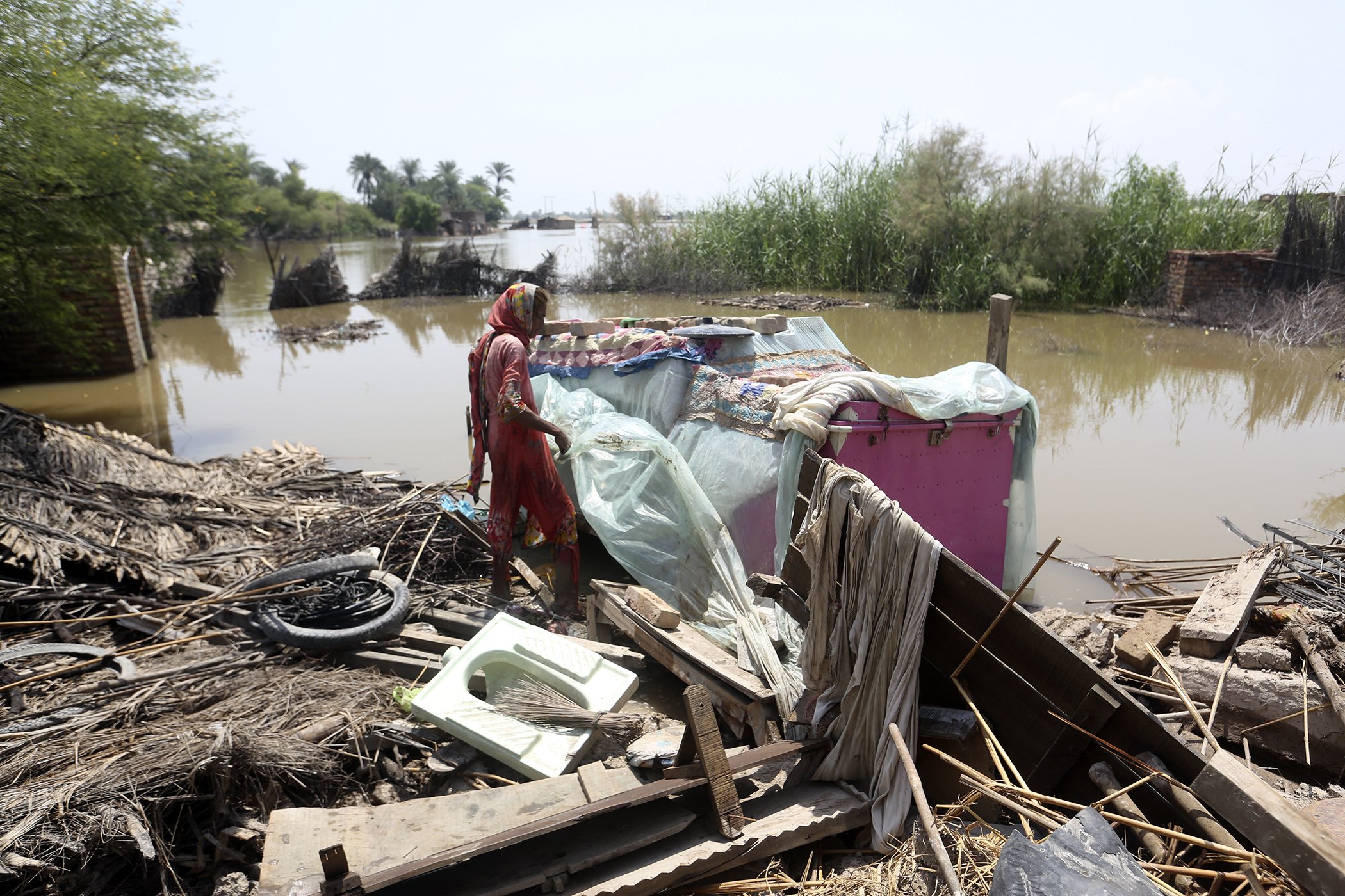 Muktiyara Bibi looks for salvageable belongings from her flood-hit home in Shikarpur district, Sindh province, Pakistan, on Aug. 30, 2022.