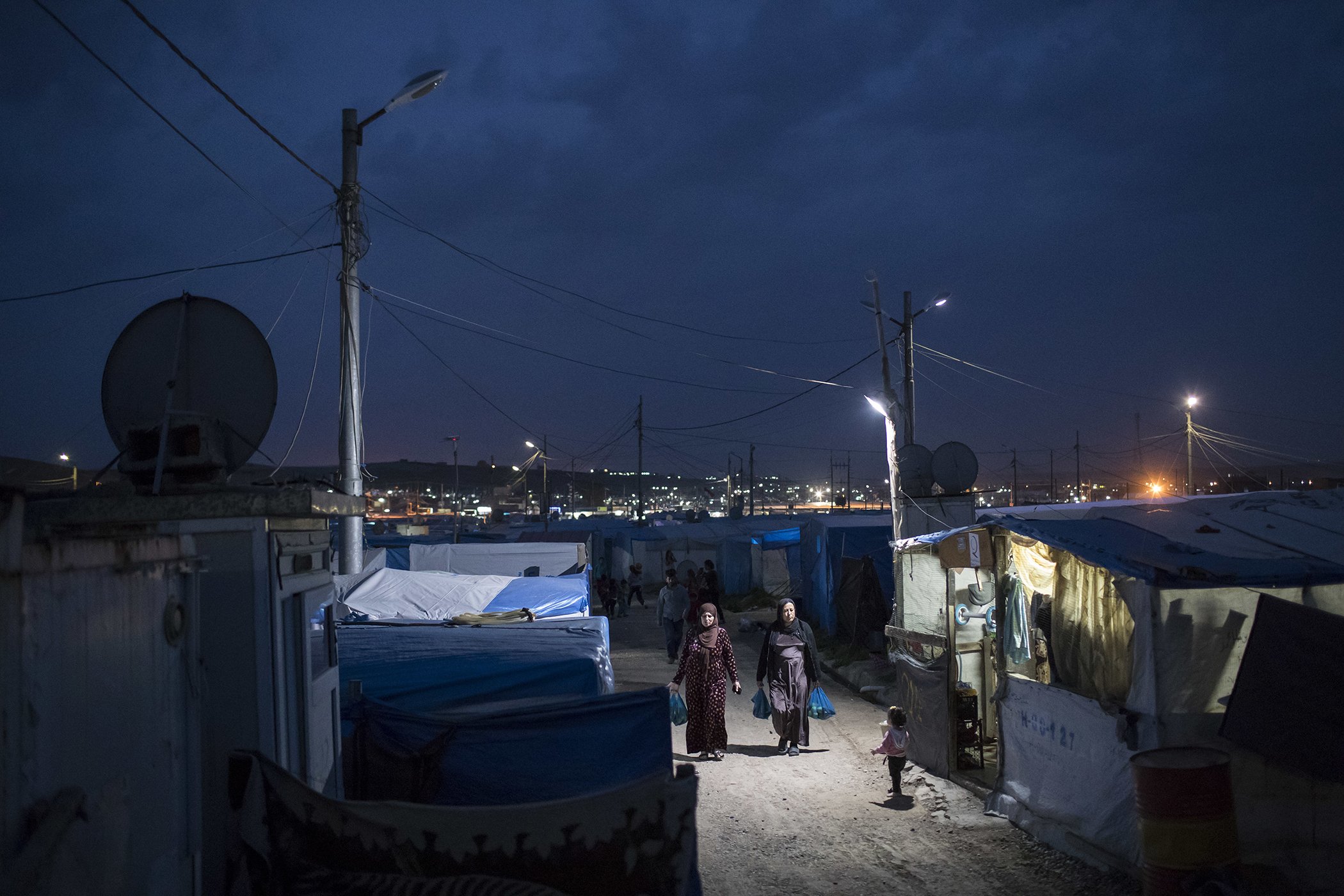 Syrian women walk through the Kawergosk refugee camp in northern Iraq, at dusk on in April 2017.