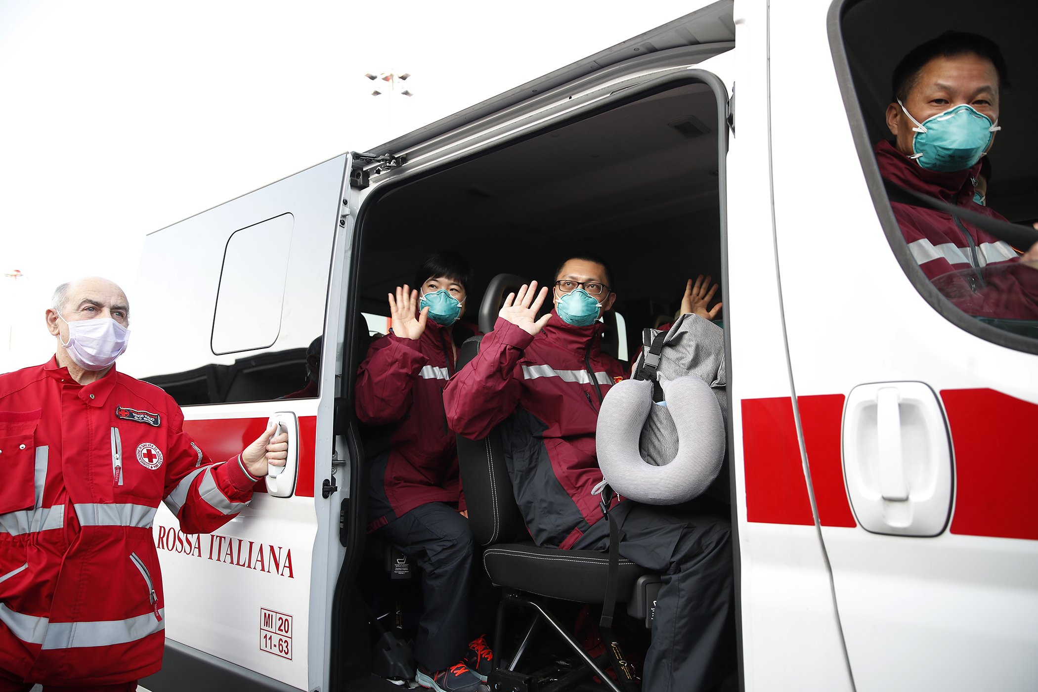 Medics and paramedics from China wave as they arrive at the Malpensa airport of Milan, March 18, 2020. Some 37 doctors and paramedics were sent along with some 20 tons of equipment, to be deployed to different hospitals in Italy's most affected area.
