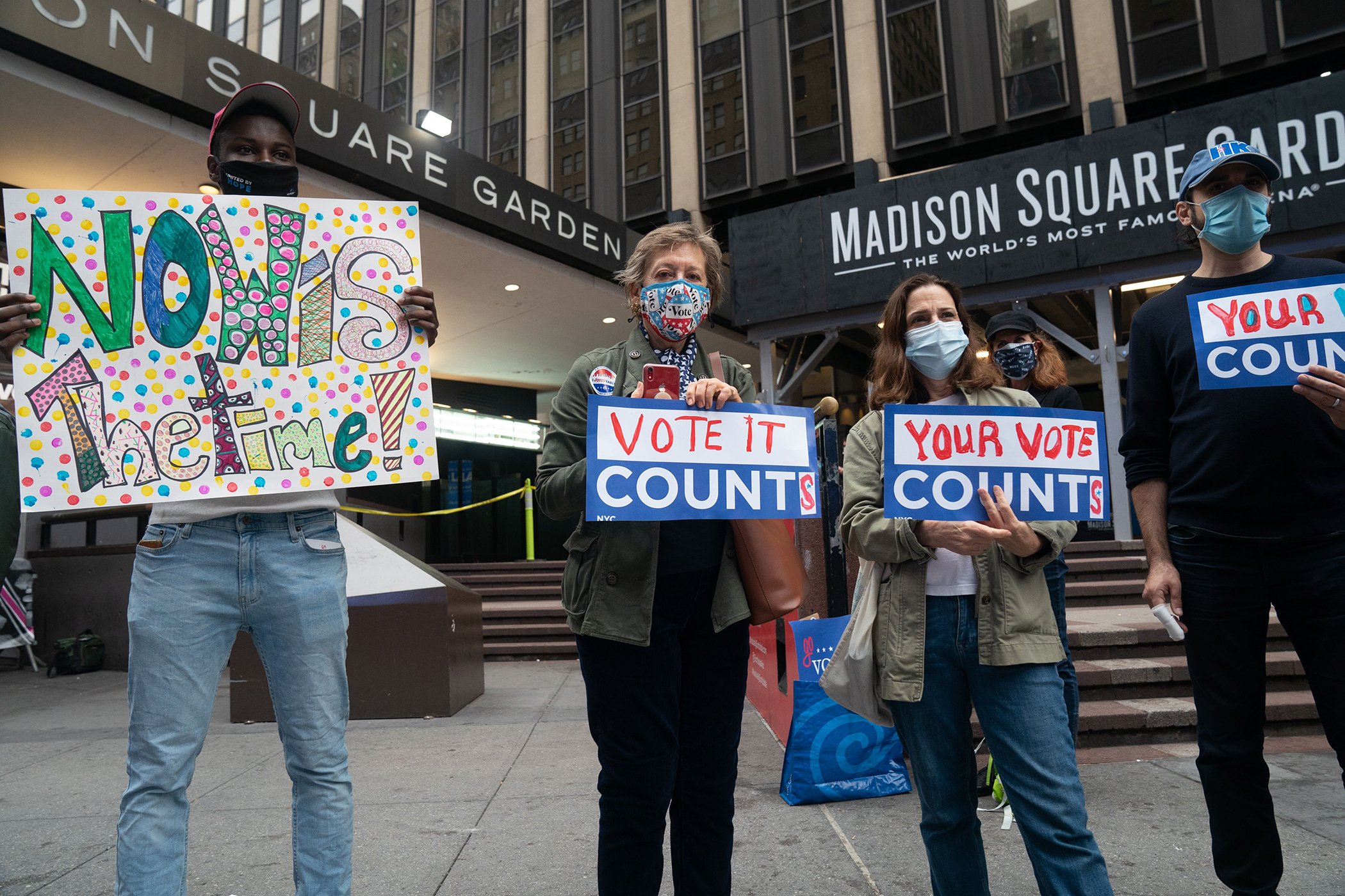 People hold signs outside Madison Square Garden on the first day of early voting, in New York City on Oct. 24, 2020.