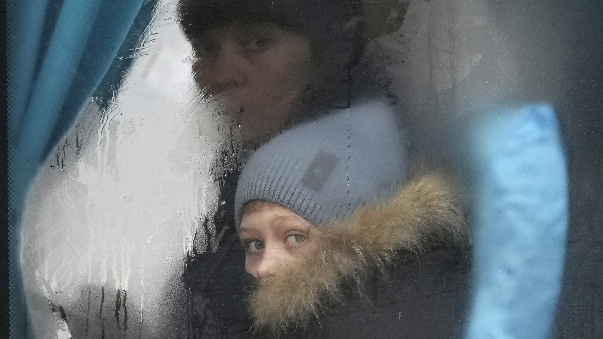 A woman and child peer out of the window of a bus as they leave Sievierodonetsk, the Luhansk region, eastern Ukraine, Feb. 24, 2022.