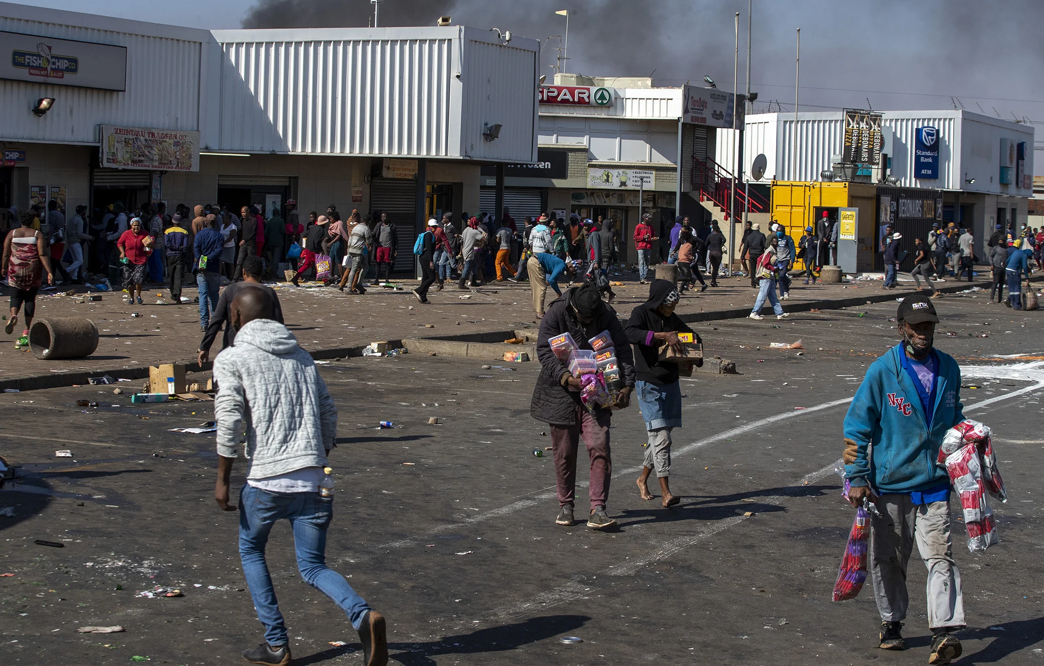 People carrying groceries looted at Letsoho Shopping Centre in Katlehong, east of Johannesburg, South Africa, July 12, 2021.