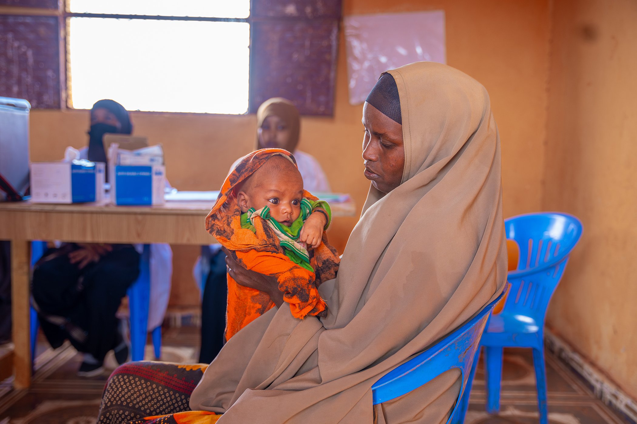 Muslima Ahmed holds her child as she waits for him to receive a vaccination at the outreach vaccination facility in Walaag 1 IDP camp in Baidoa, Somalia in September 2024. This effort is a part of the Reach Zero Dose Children campaign in Somalia.