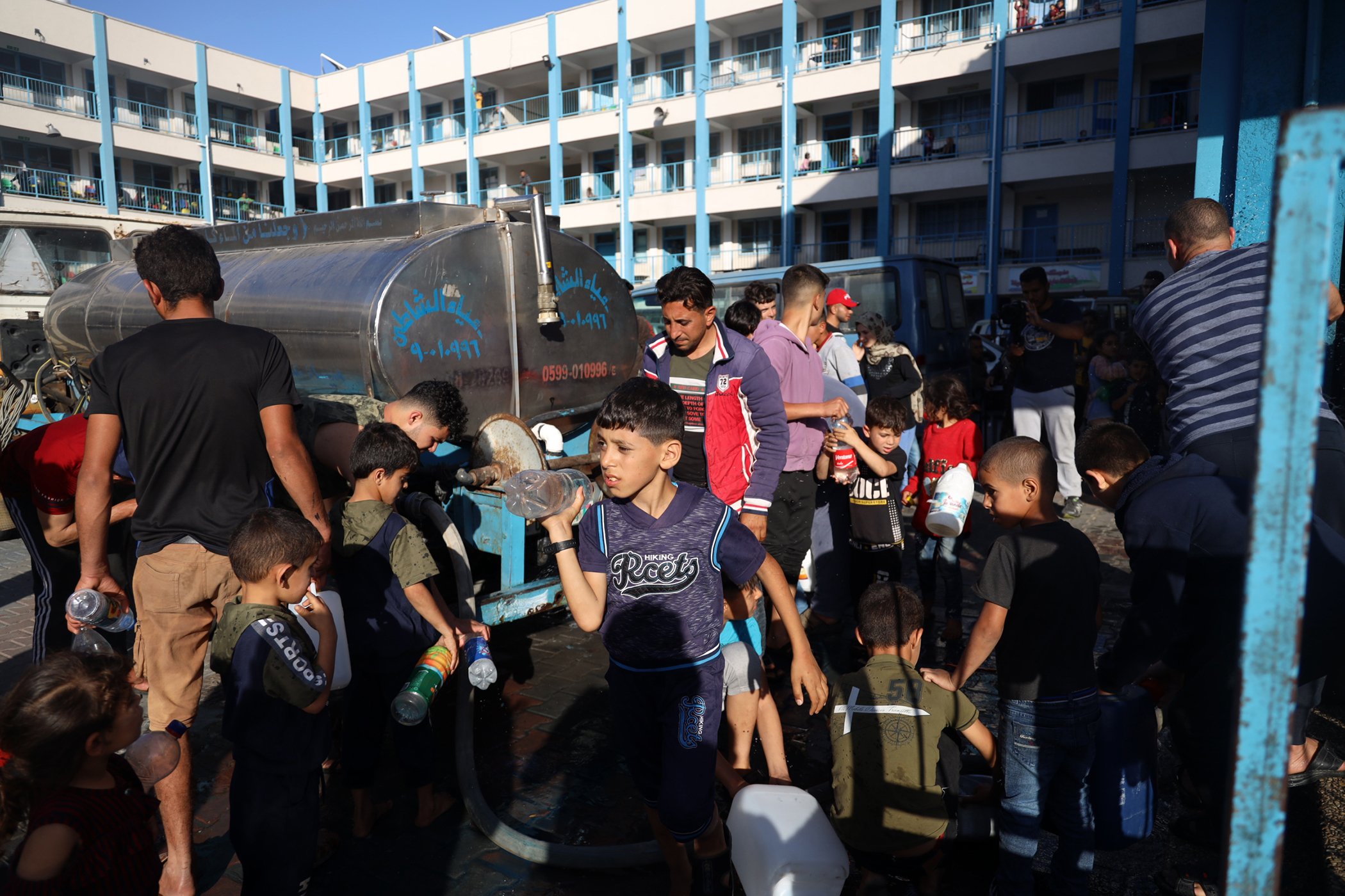 People gather at a water truck to fill bottles with clean drinking water on May 15, 2021 in Gaza. Gaza already suffered from a shortage of clean drinking water, but the current violence makes access to clean water significantly more difficult.