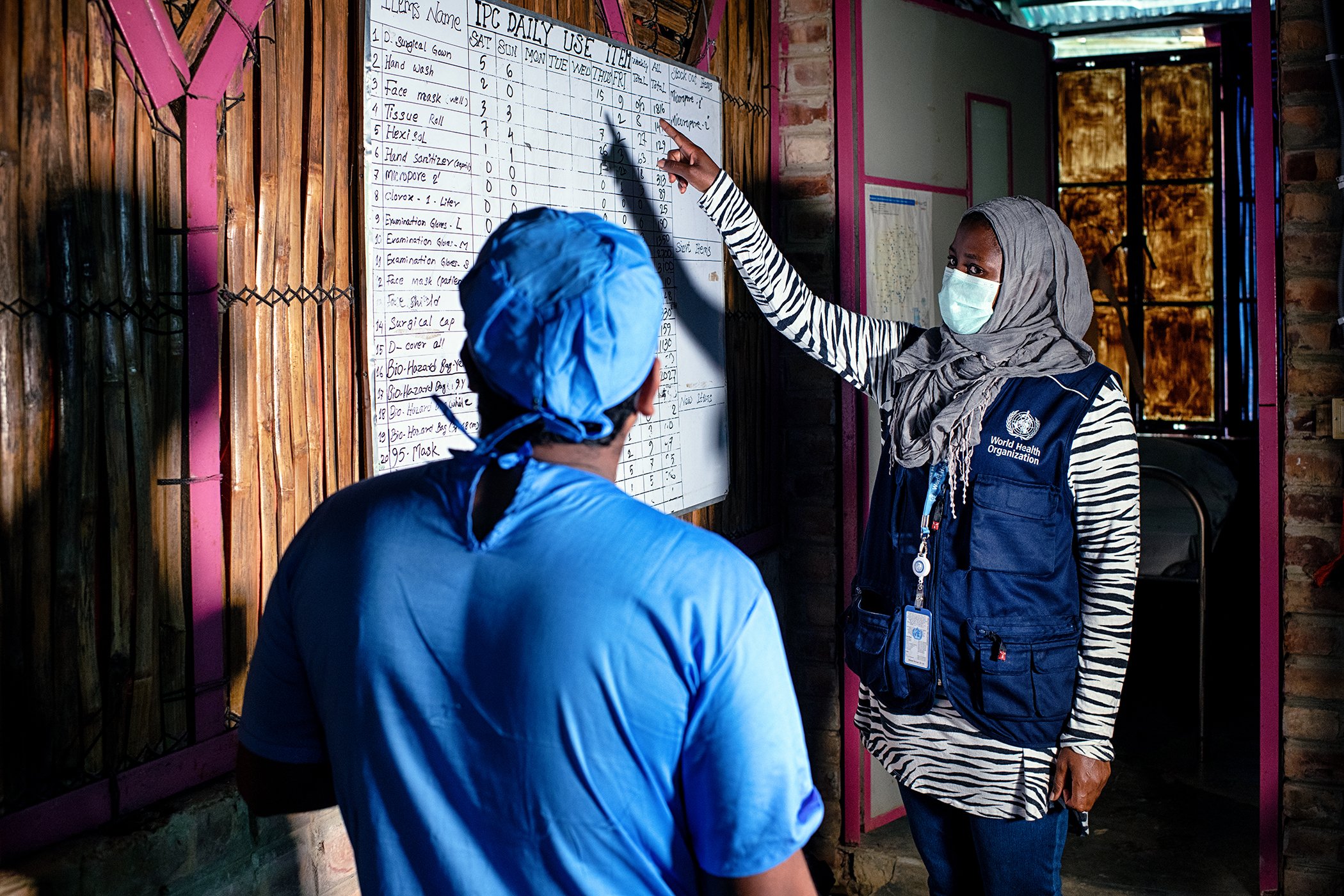 WHO Infection Prevention and Control Specialist Rebecca Rachel Apolot (right) speaks with a doctor at a Severe Acute Respiratory Infection Isolation and Treatment Center (SARI ITC) in a Rohingya camp.