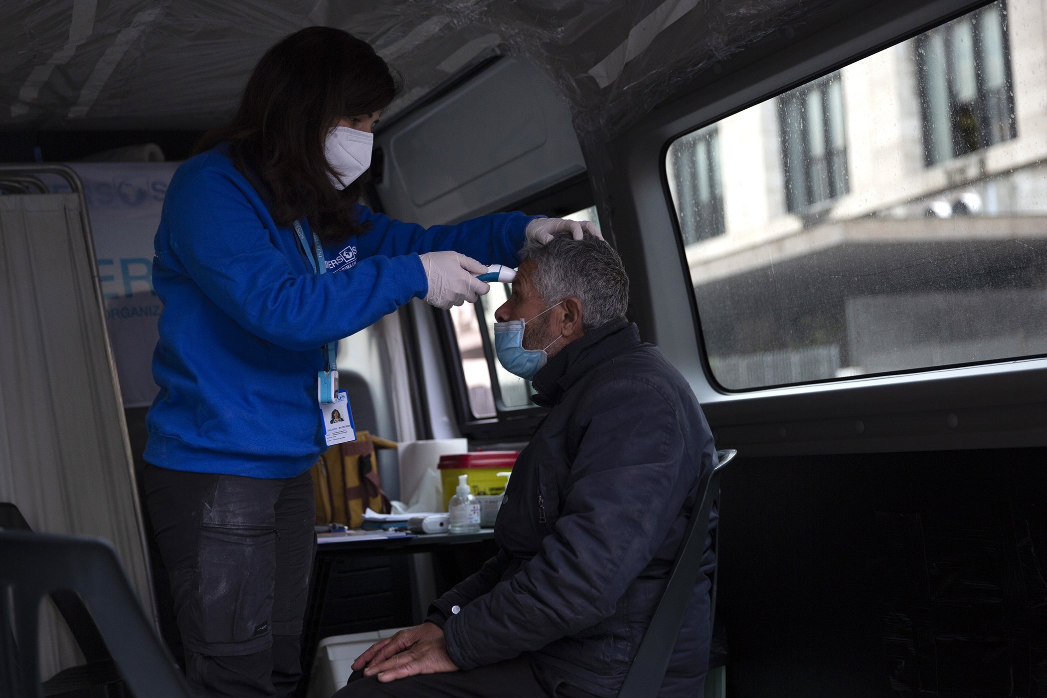 Antonella Torchiaro, a doctor for INTERSOS Humanitarian Aid Organization, checks the temperature of man in a road unit placed at Rome's Termini station, March 25, 2020.