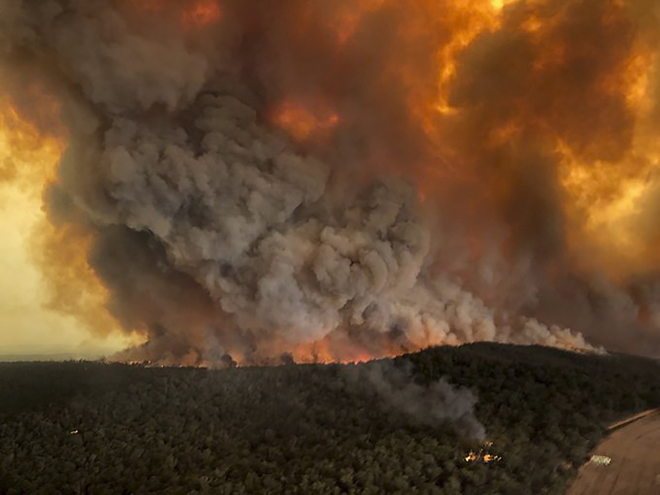In this Monday, Dec. 30, 2019, aerial photo, wildfires rage under plumes of smoke in Bairnsdale, Australia.