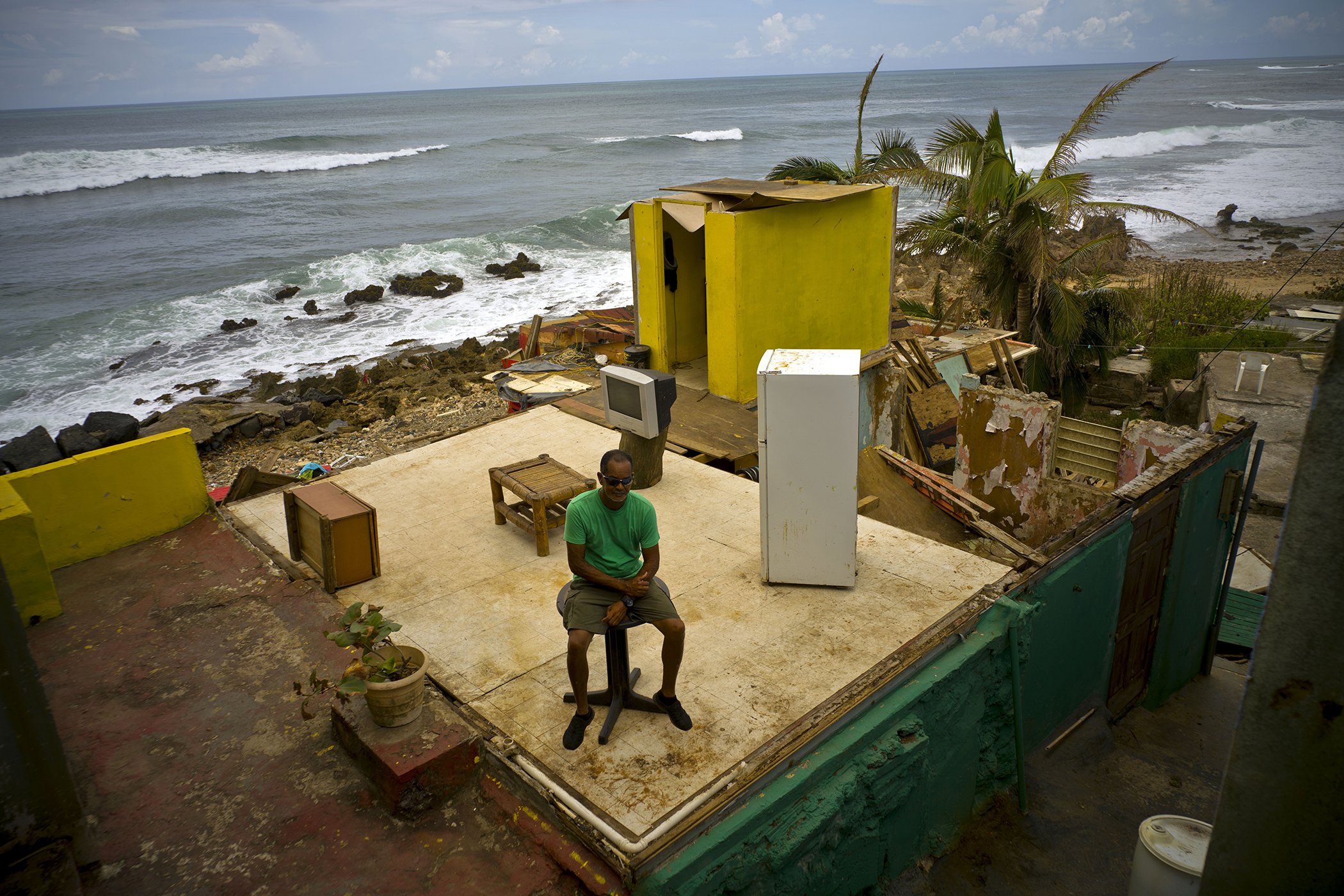 Roberto Figueroa Caballero sits on a small table in his home that was destroyed by Hurricane Maria in La Perla neighborhood on the coast of San Juan, Puerto Rico on Oct. 5, 2017.