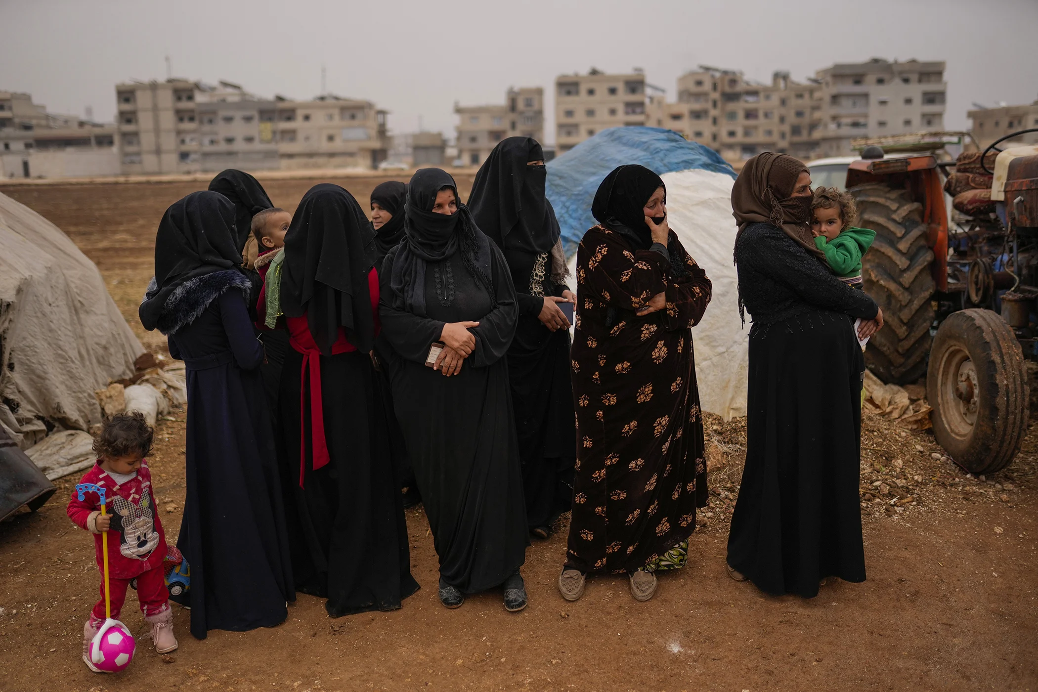 Syrian women wait for donated food to be distributed in a refugee camp for displaced people supported by the Turkish Red Crescent in Sarmada district, north of Idlib city, Syria, Nov. 25, 2021.