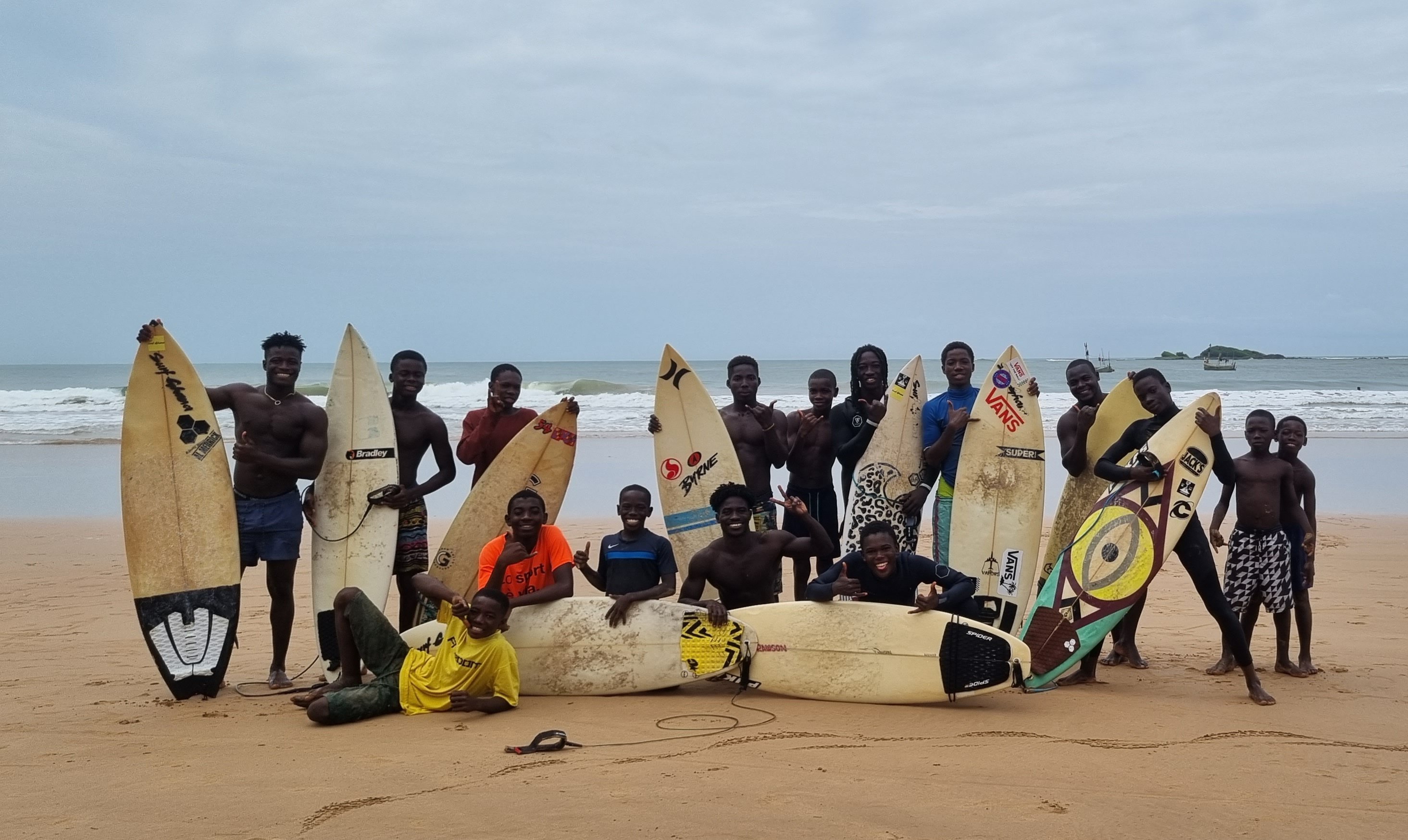 Members of Ahanta Waves Surf School & Camp pose for a photo with their surfboards on the Busua Beach