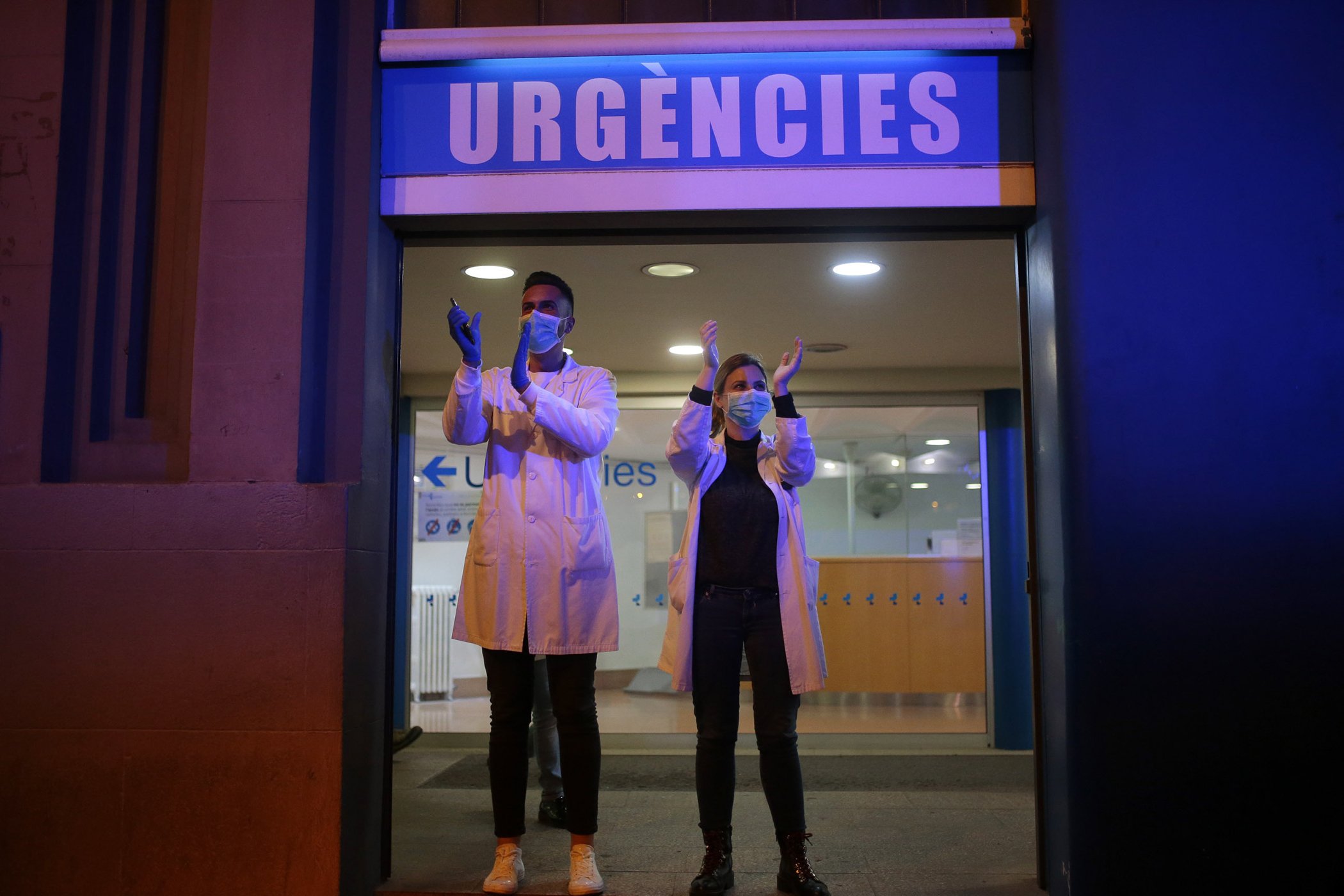 Health workers react as people applaud from their houses in support of the medical staff that are working in COVID-19 outbreak in Barcelona, Spain, March 16, 2020.