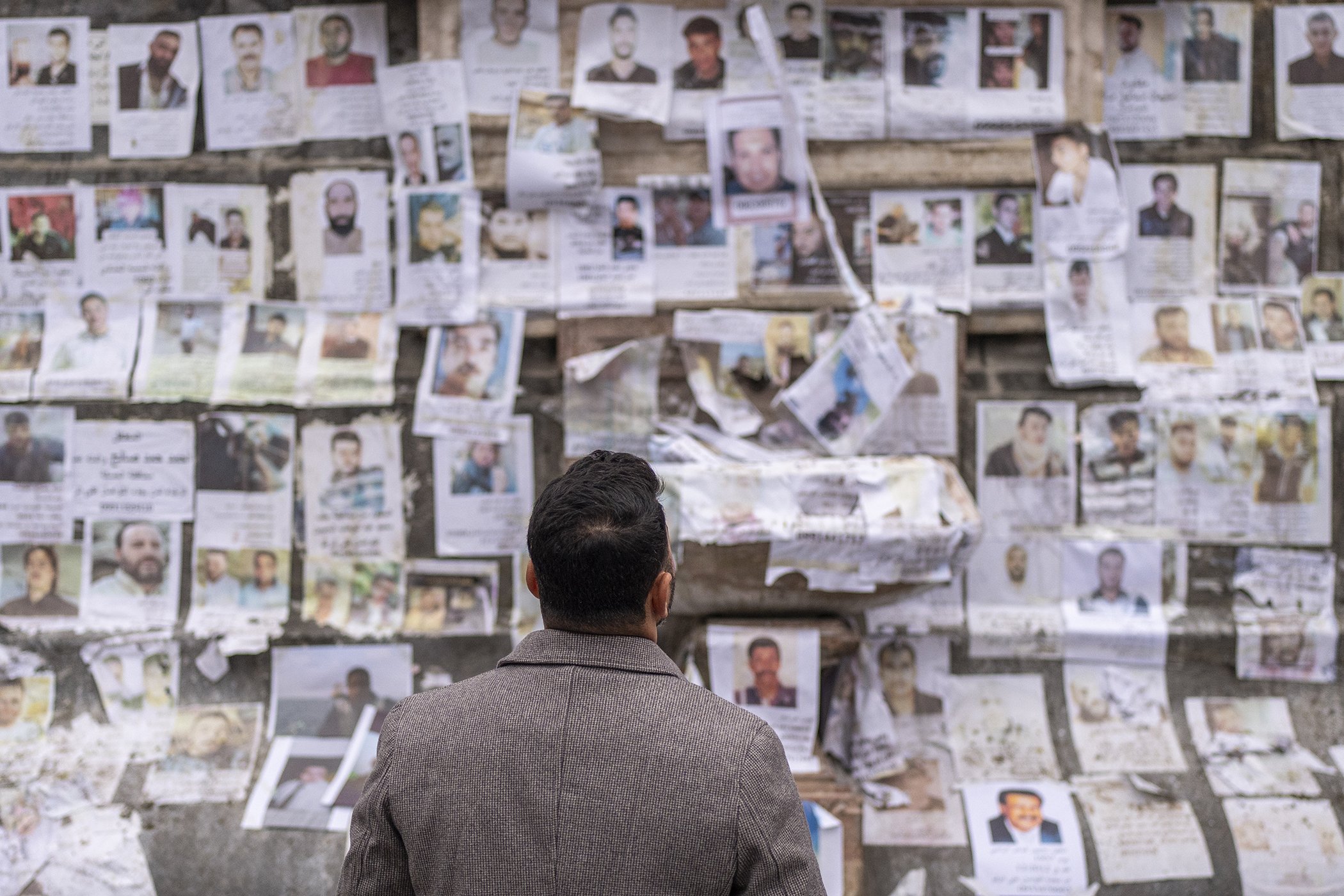 A man looks at portraits of missing people whose families say they were taken by the Assad regime are plastered across a monument in Damascus, Syria, Dec. 28, 2024.