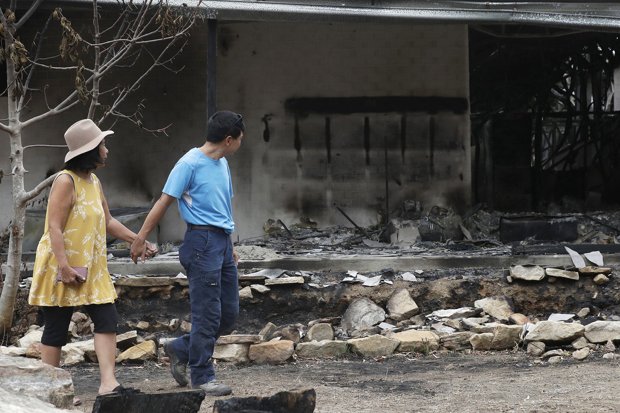 Justin Kam, right, and Helena Wong survey their destroyed home at Balmoral, Australia, Jan. 7, 2020.